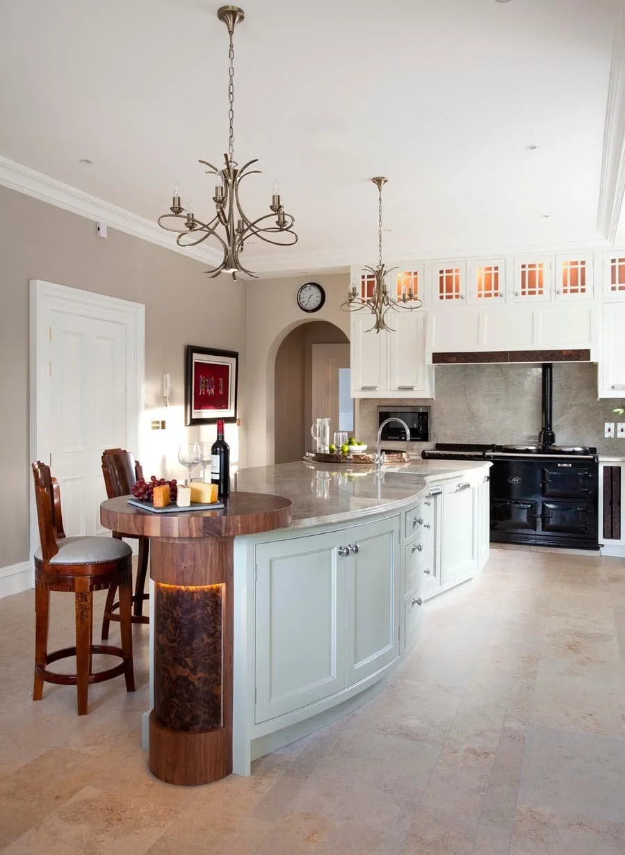 Bright bespoke kitchen with an Aga, white cabinetry, curved island and timber breakfast bar.