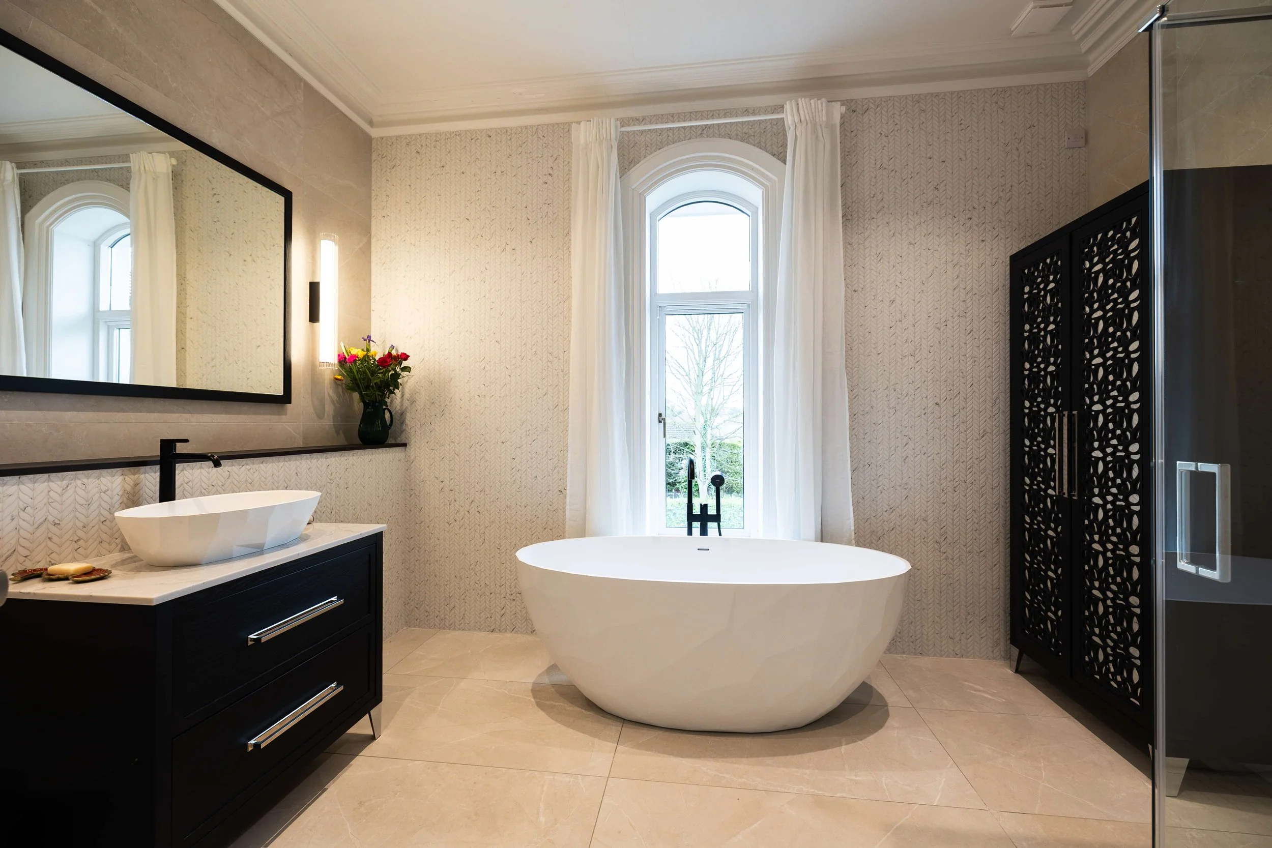 Completed luxury bathroom with freestanding bath, bespoke vanity and arched windows.