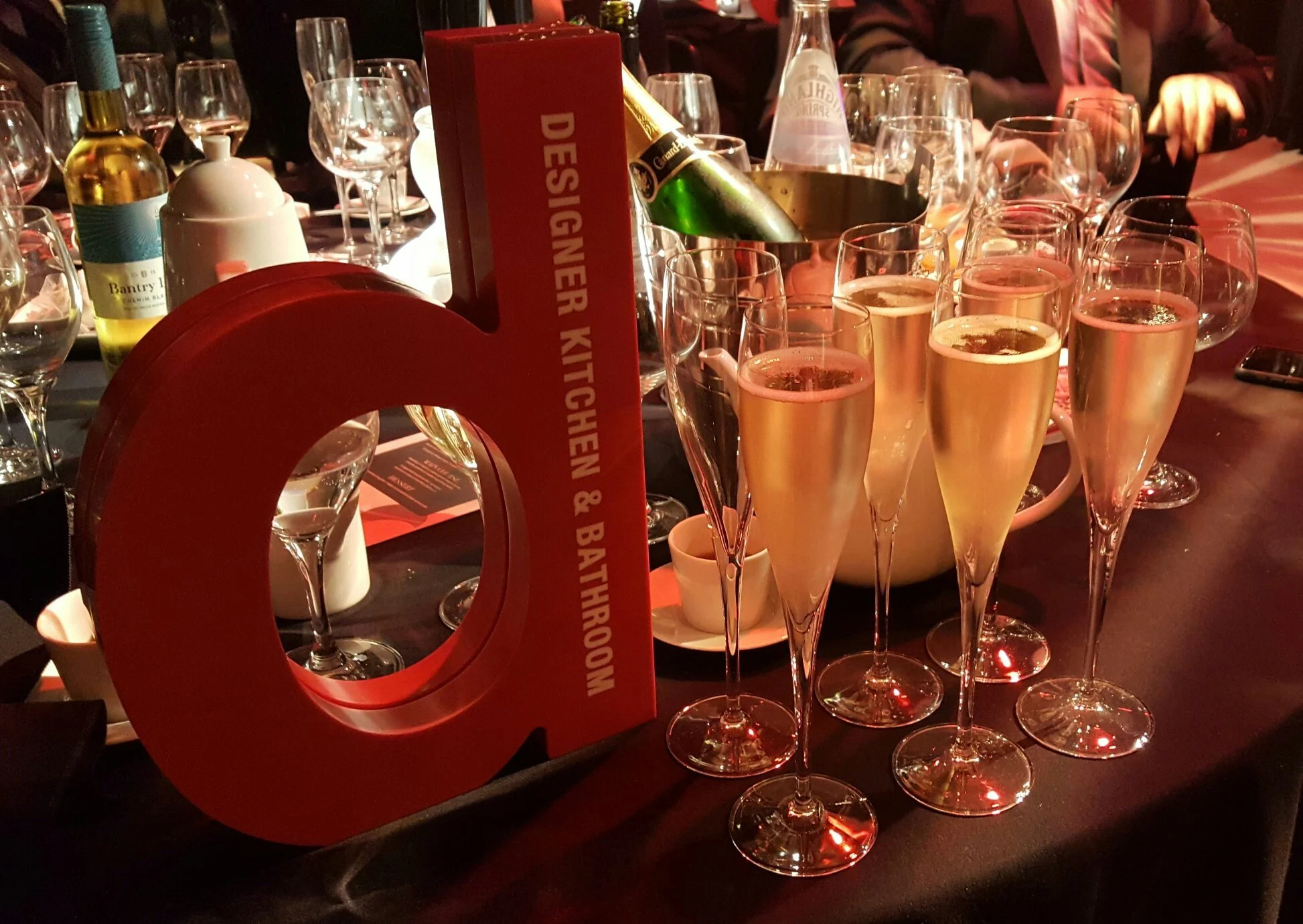 Designer award trophy displayed with wine and glasses at an industry awards event.