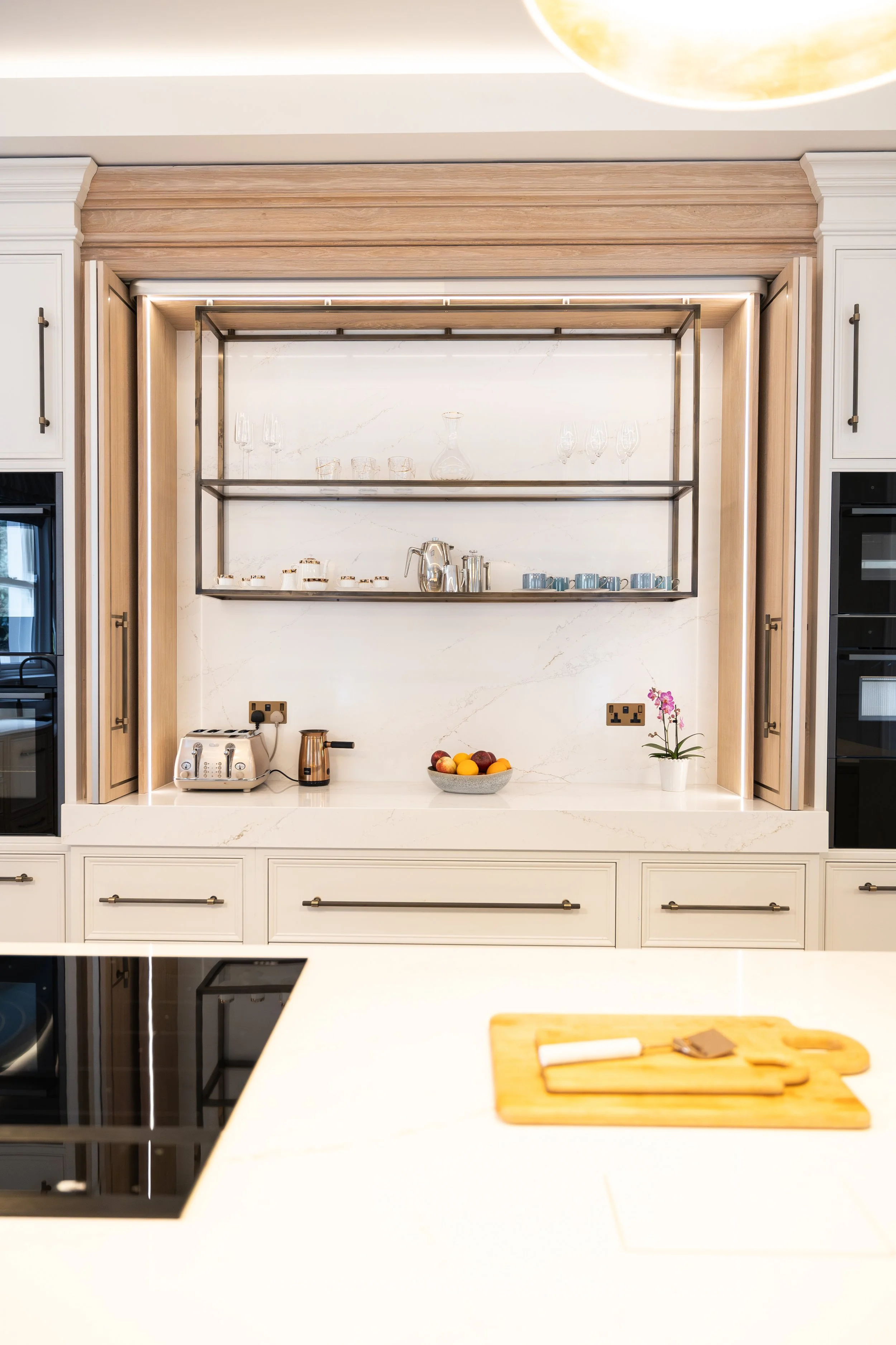 Completed classic kitchen with white cabinetry, stone worktop and brass detailing.