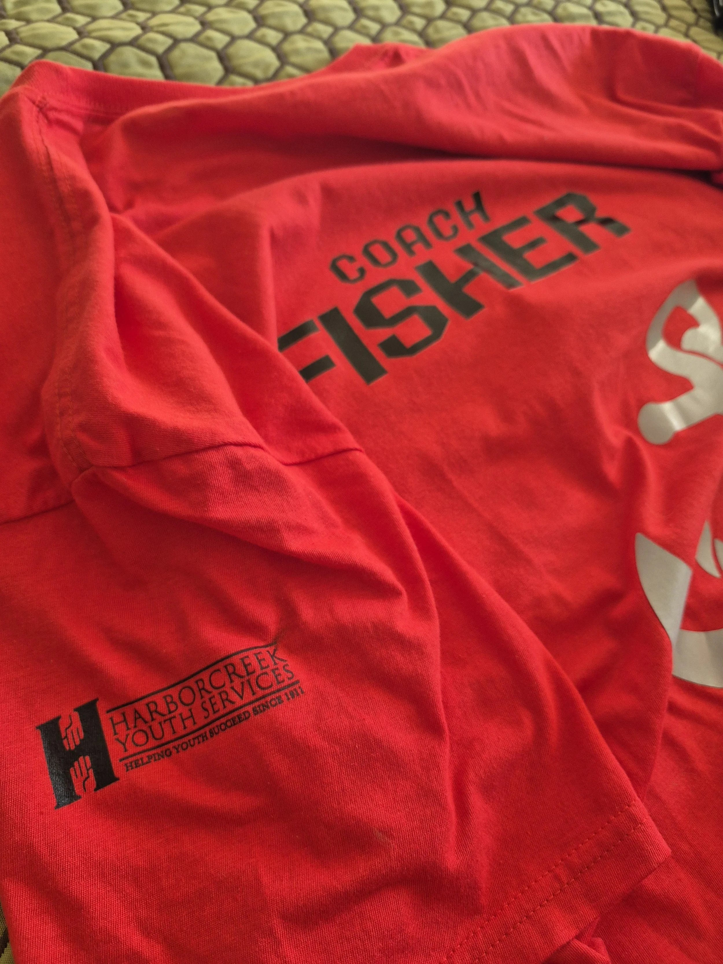 A red "Coach Fisher" flag football jersey sponsored by Harborcreek Youth Services