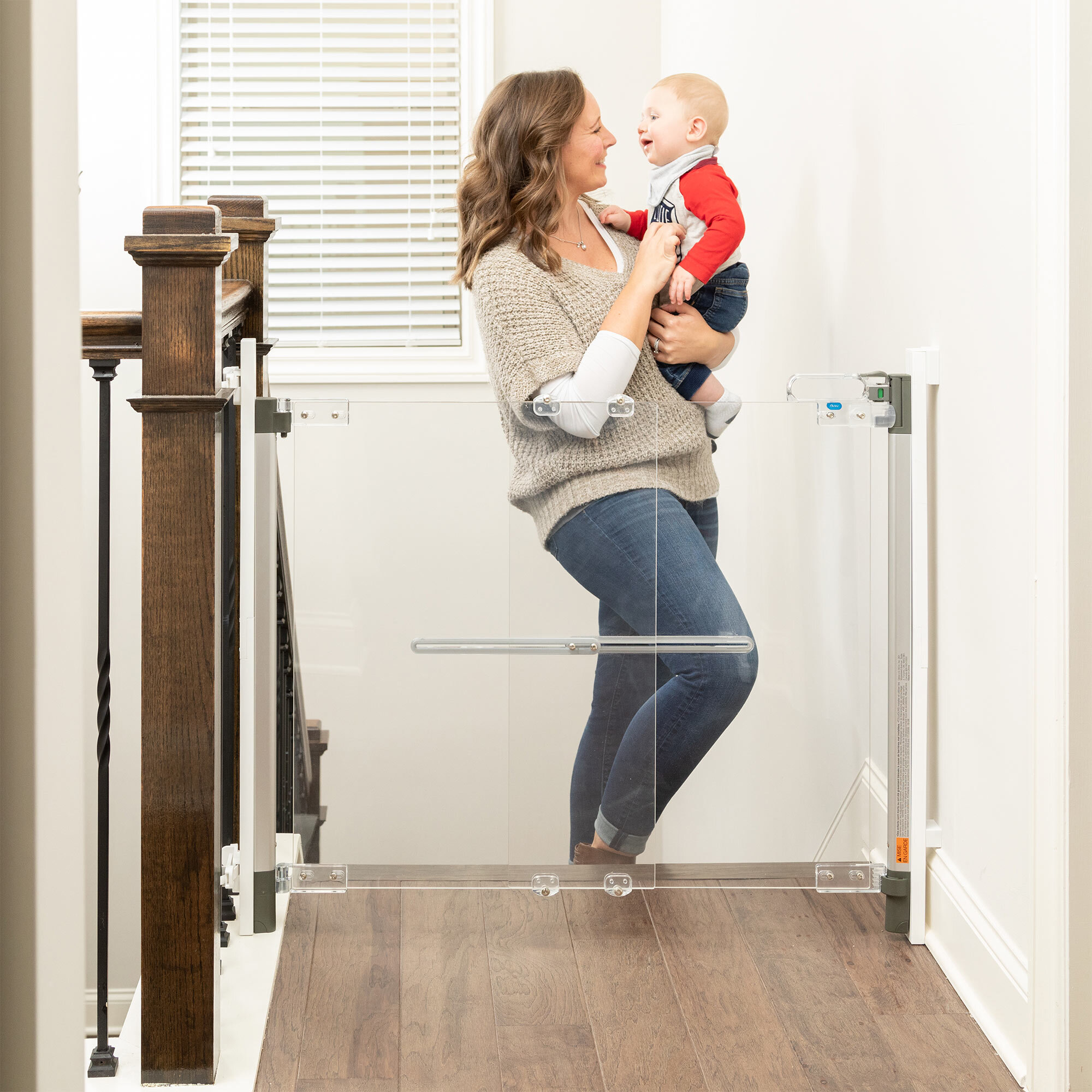 Mother standing behind Crystal® Designer Baby Gate at top of stairs