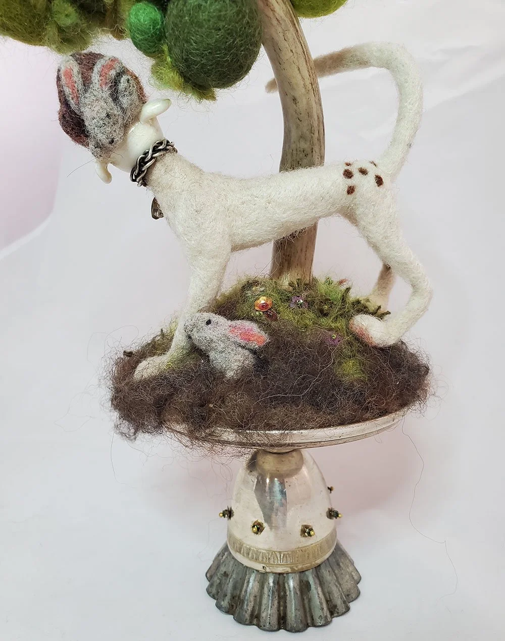 detail showing needlefelted rabbits on a needlefelted sculpture of dog with lampworked glass head under a tree with a trunk made from deer antler