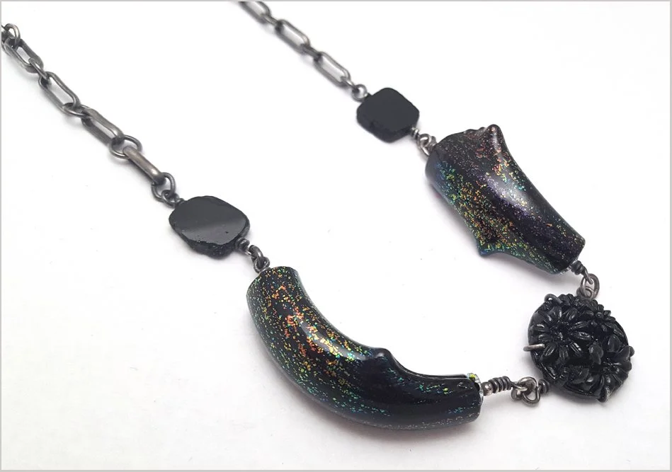 oxidized silver necklace with black tourmaline beads and curved handblown dichroic glass with glass button center