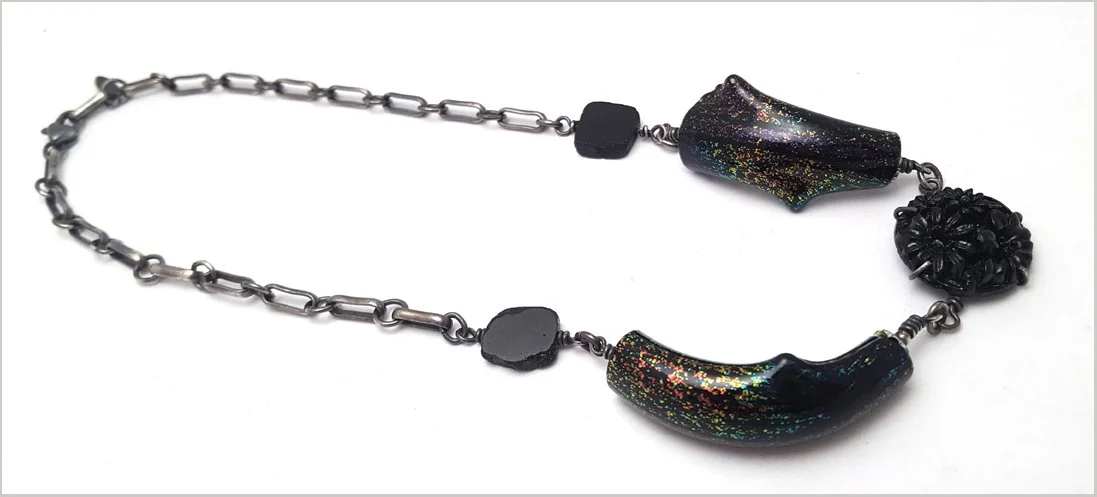 oxidized silver necklace with black tourmaline beads and curved handblown dichroic glass with glass button center