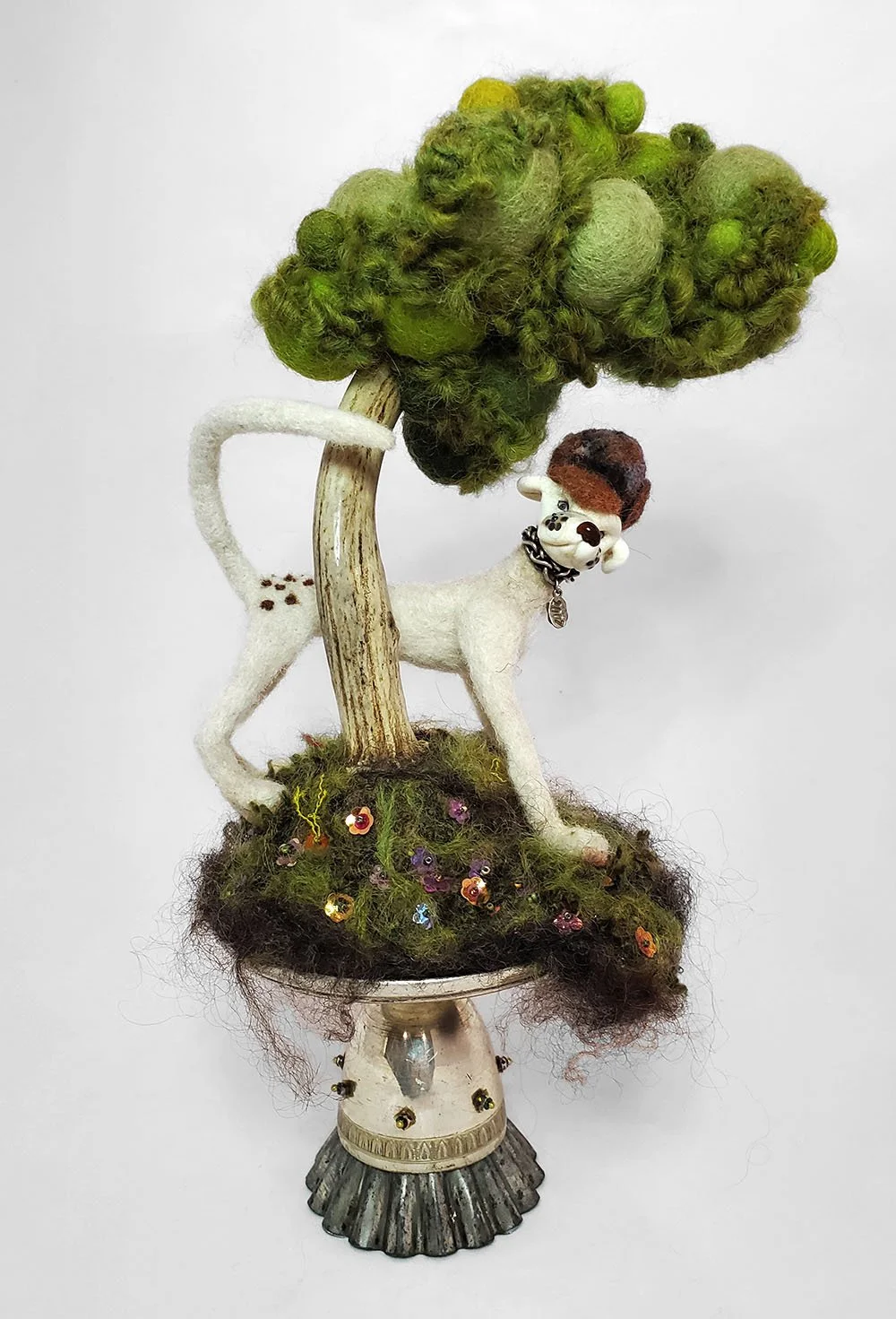 needlefelted sculpture of dog with lampworked glass head under a tree with a trunk made from deer antler