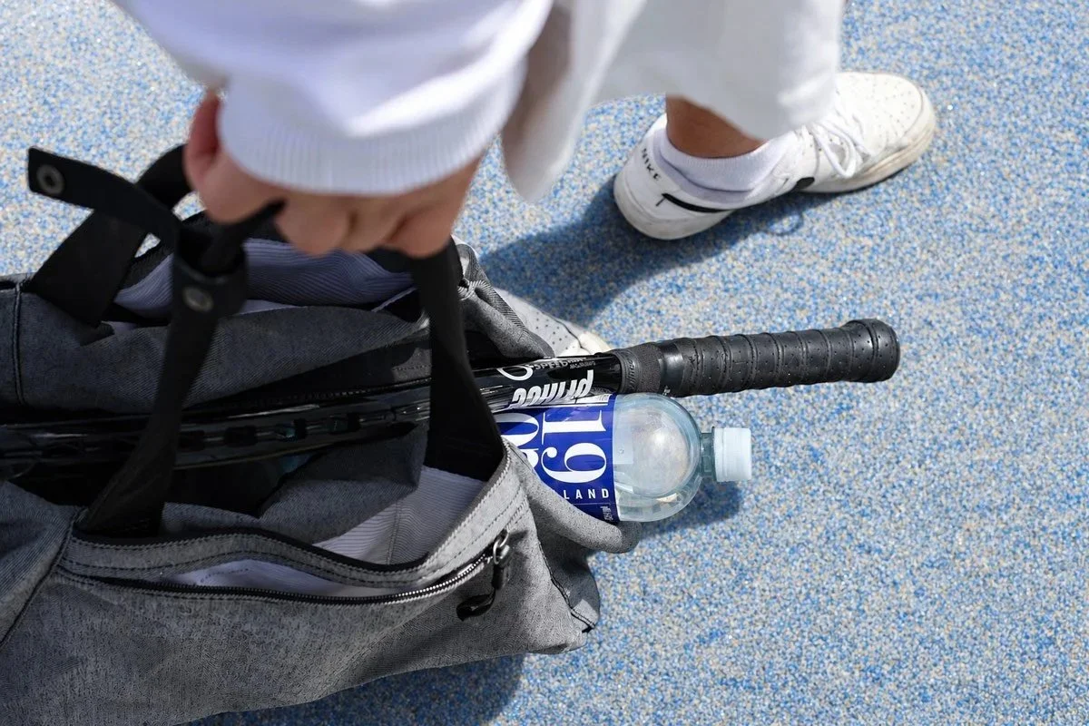 1 litre bottle of 1907 Artesian Water inside a tennis bag with racquet