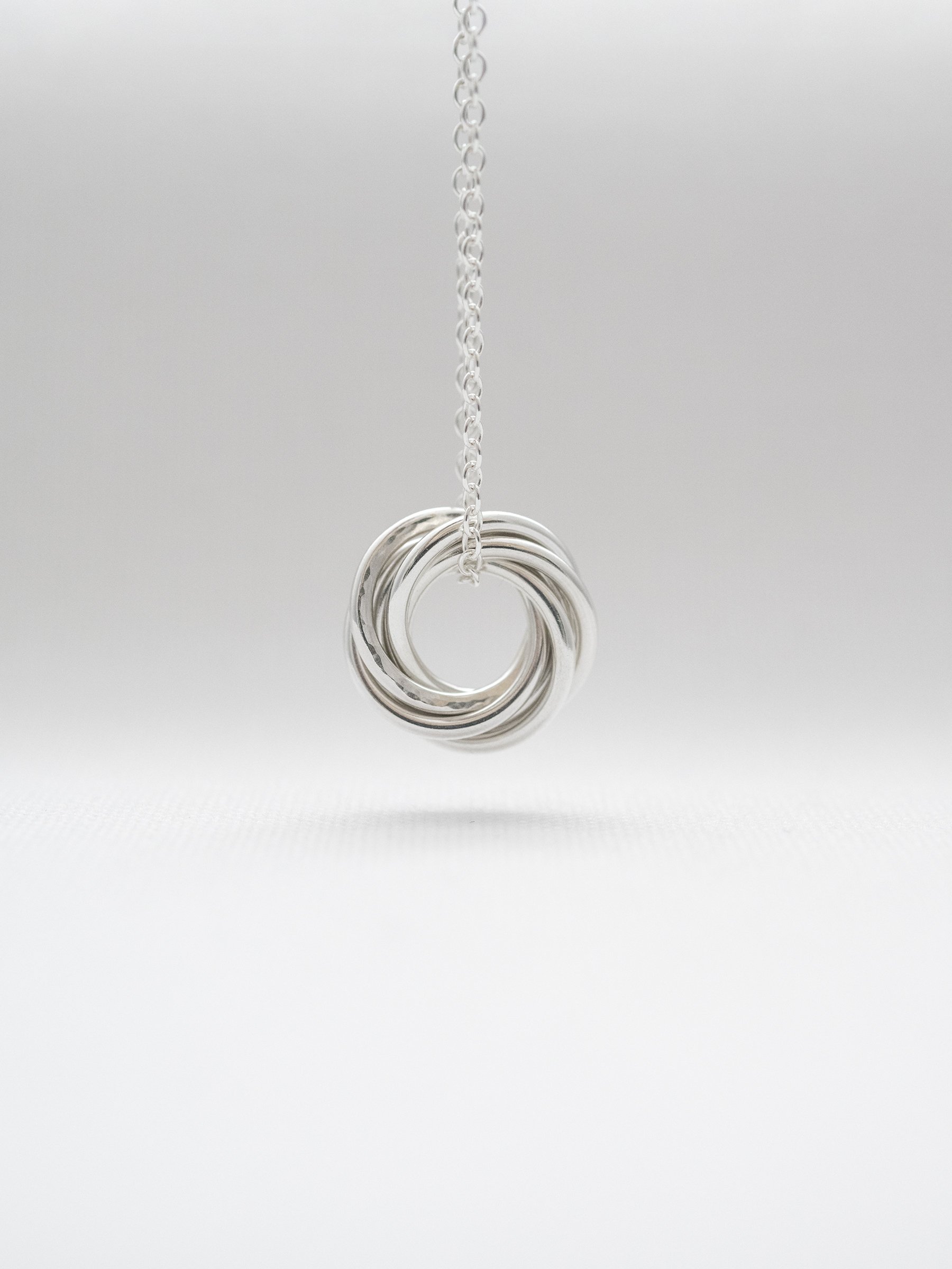 A sterling silver 60th birthday necklace hanging over white material.