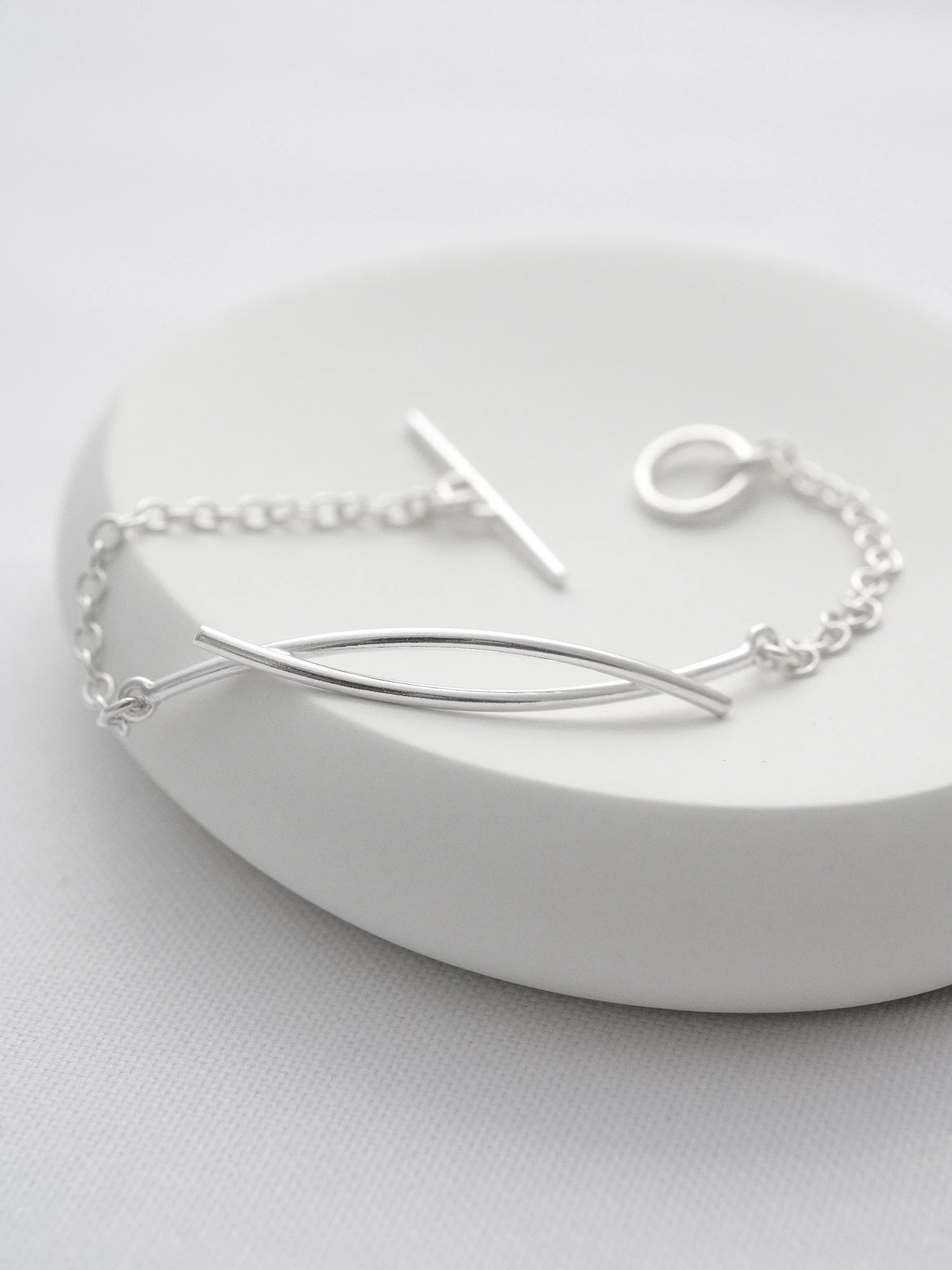 A sterling silver unique eternity bracelet displayed on a white dish.
