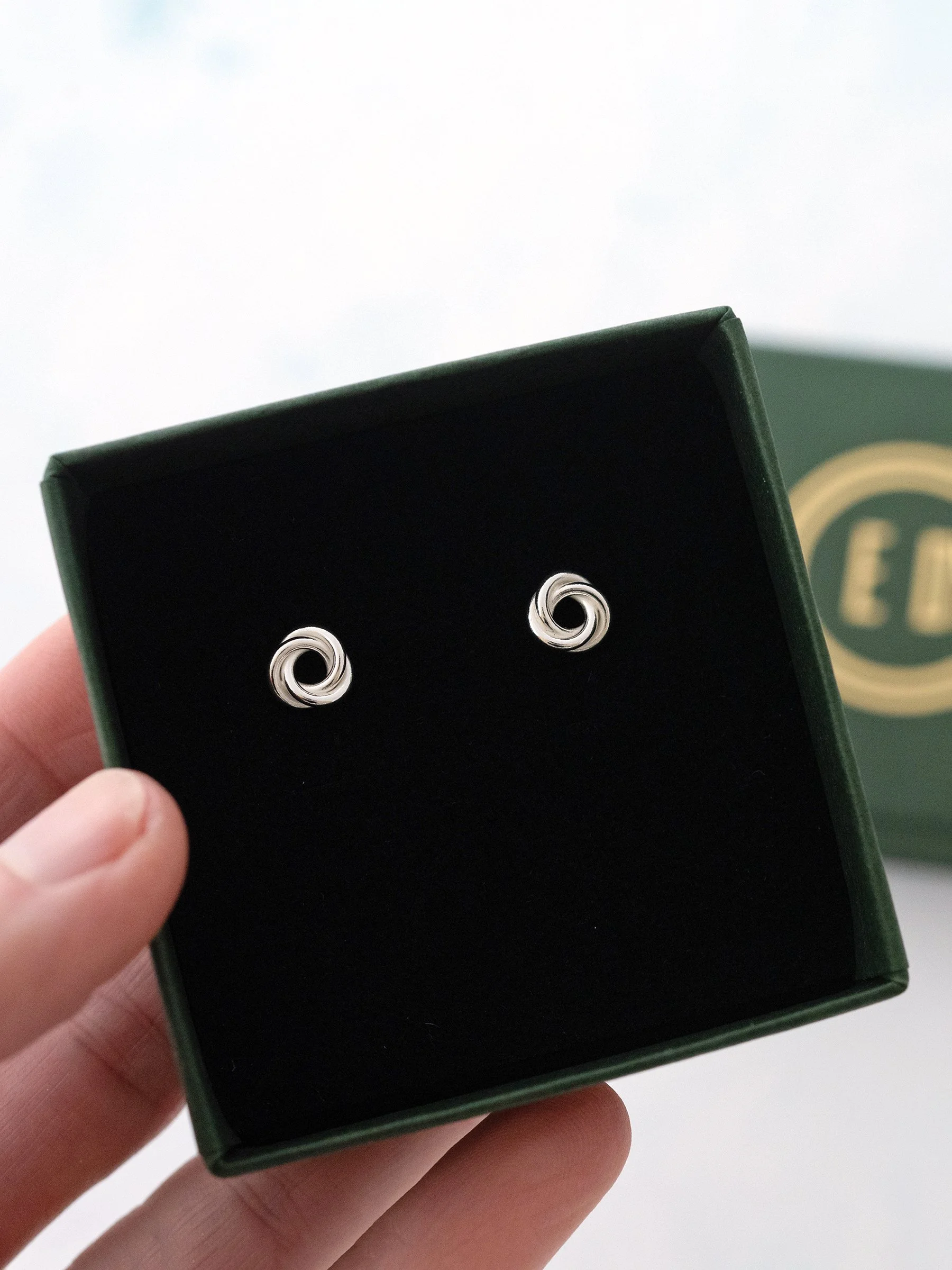 A pair of silver Russian stud earrings displayed in the presentation box.