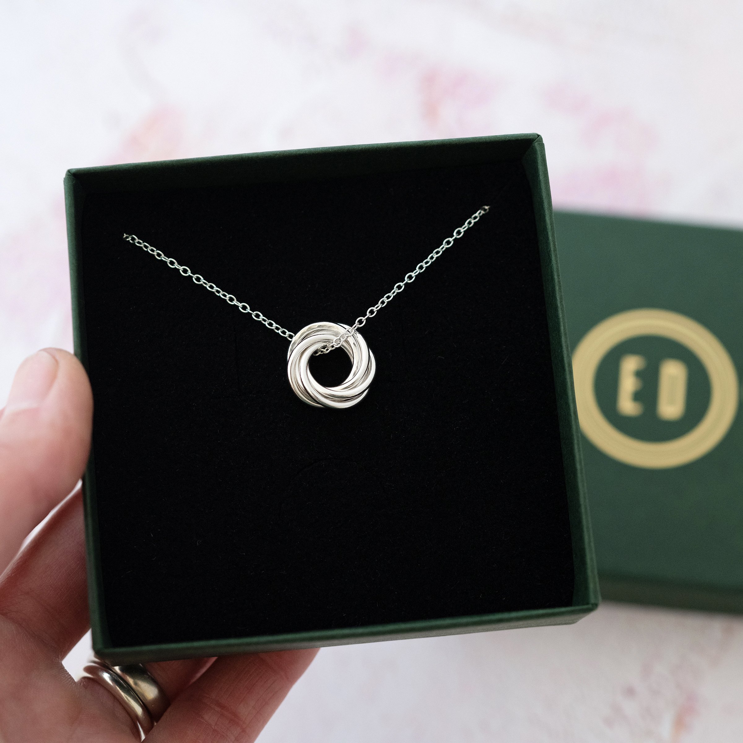 A silver 60th ring necklace displayed in a jewellery presentation box.