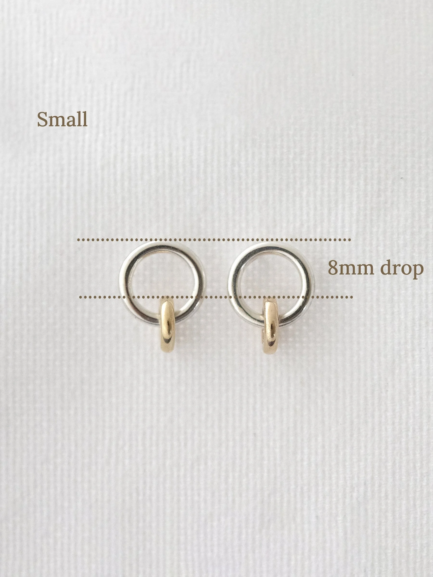 A pair of gold and silver stud earrings with markings showing the size.
