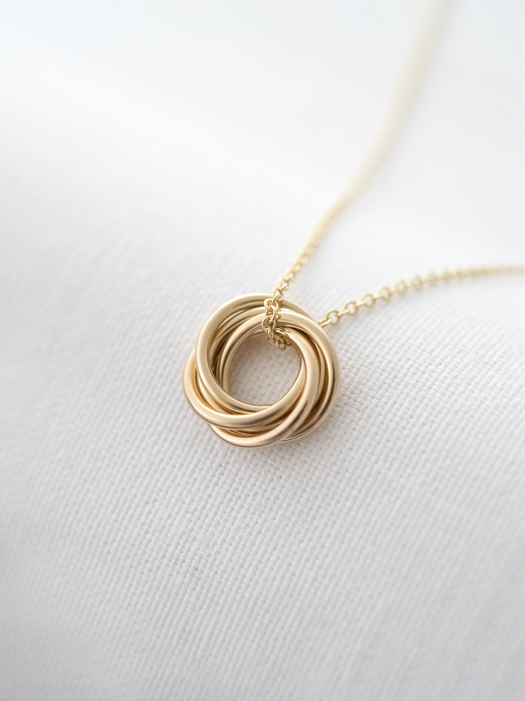 A side view of a 9ct gold 50th birthday necklace displayed over white material.