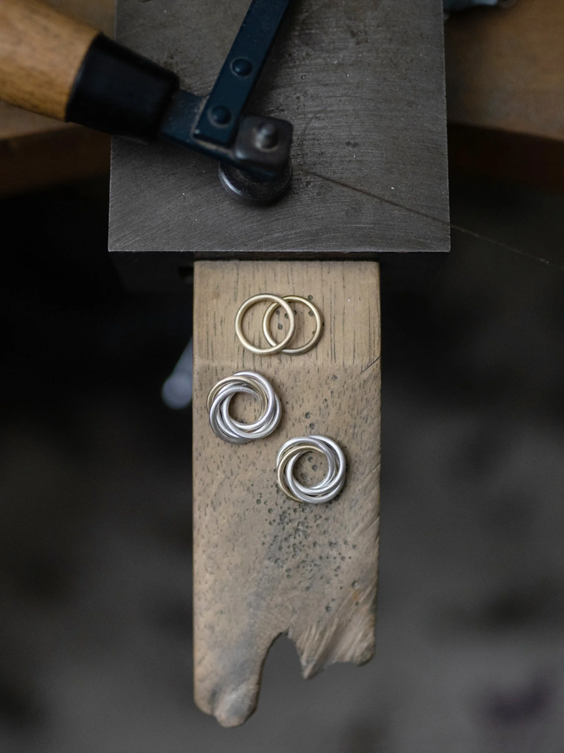 A close up of luxury gold and silver jewellery in the making on a jewellers bench peg.