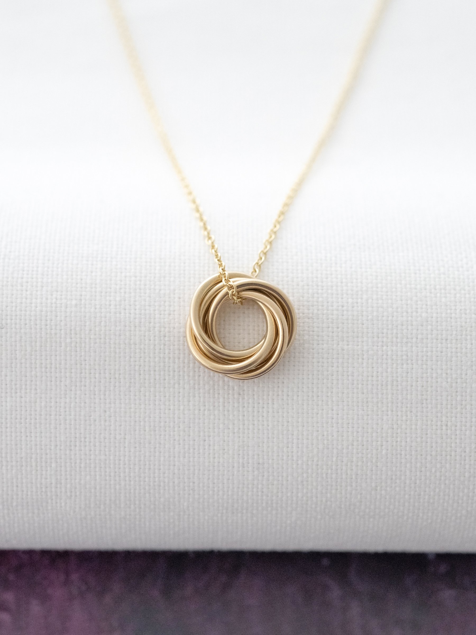 A 9ct gold 50th necklace displayed over white material.
