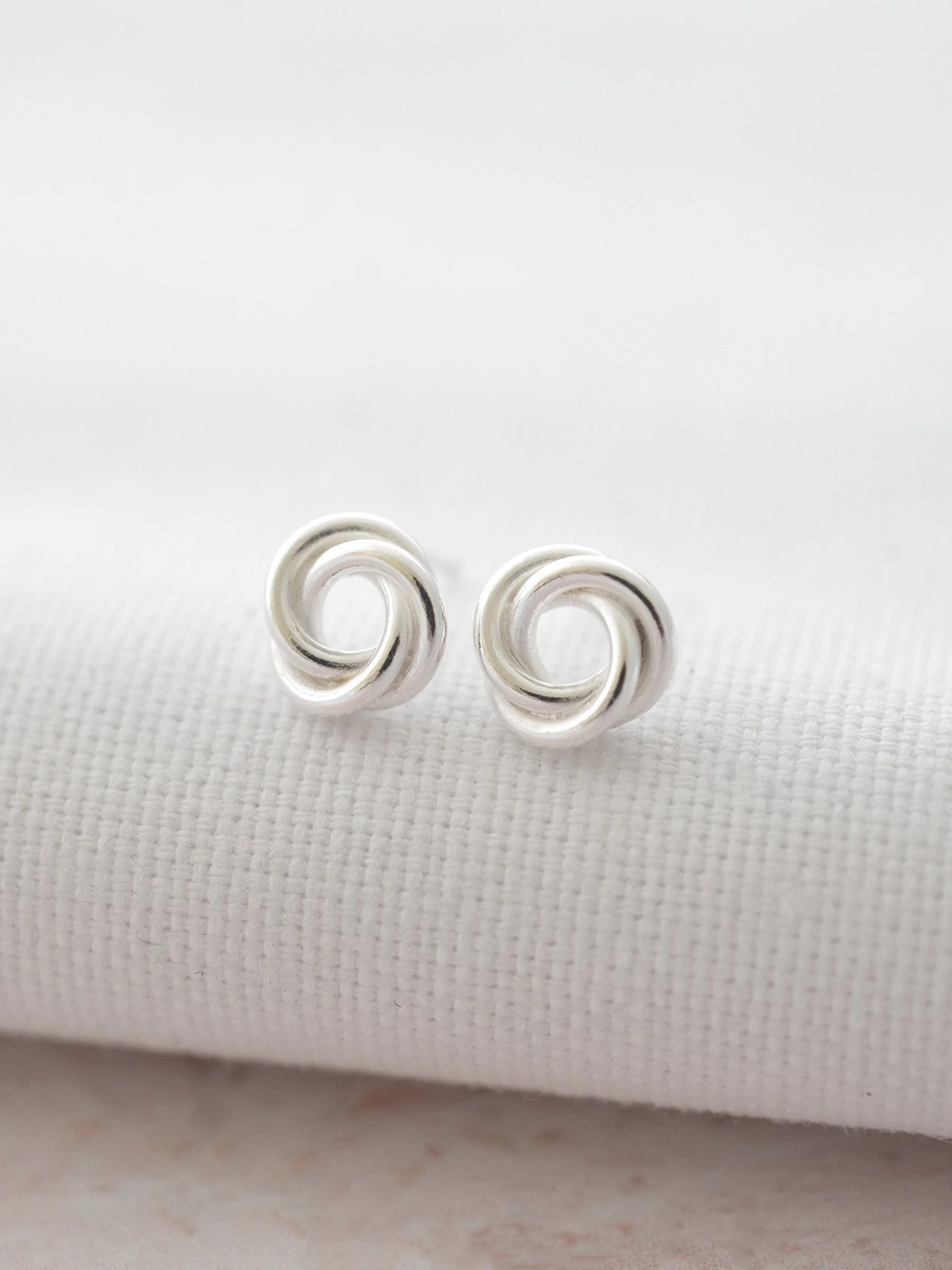 A pair of sterling silver 30th birthday earrings displayed over white material against a pale pink background.