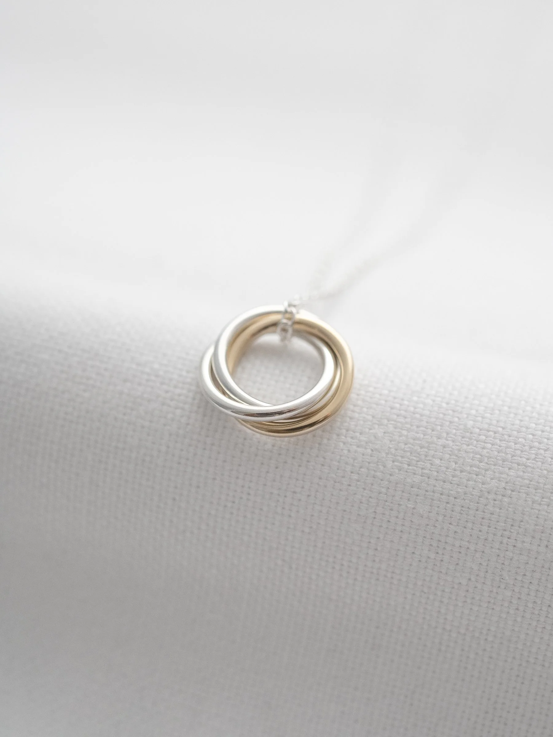 A close up of a mixed metal 30th birthday necklace displayed on white material.