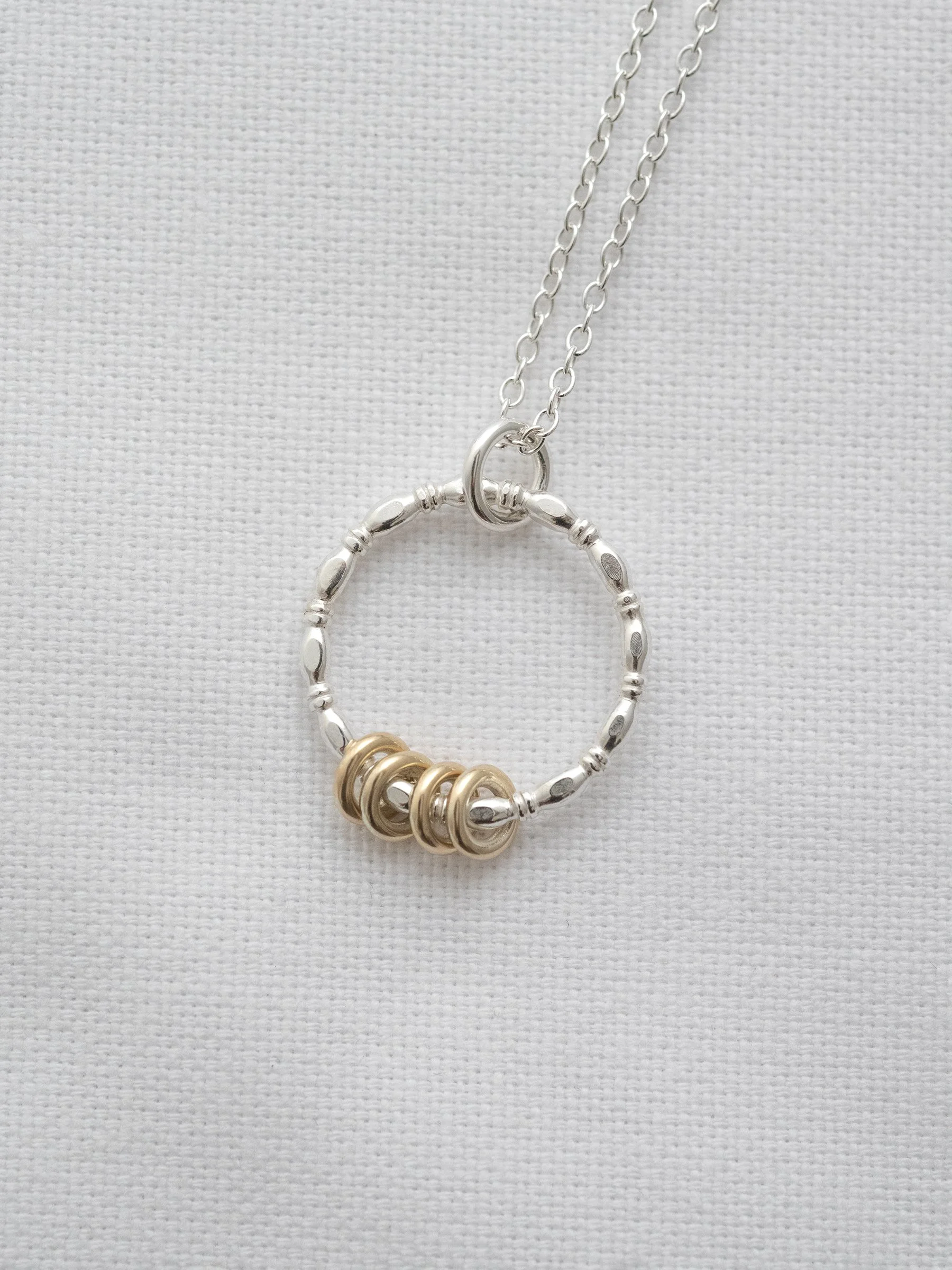 A close up of a 40th ring necklace displayed on white material.