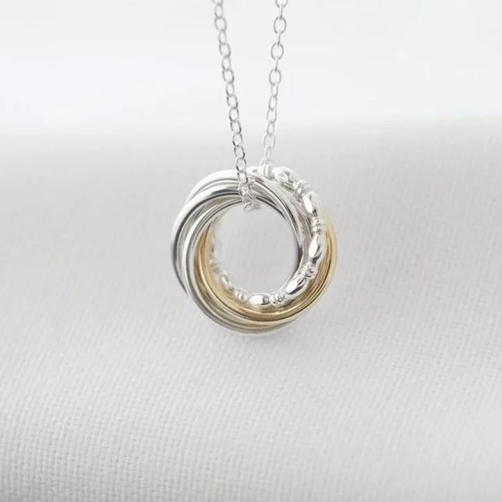 A unique gold and silver 60th birthday necklace displayed over white material.
