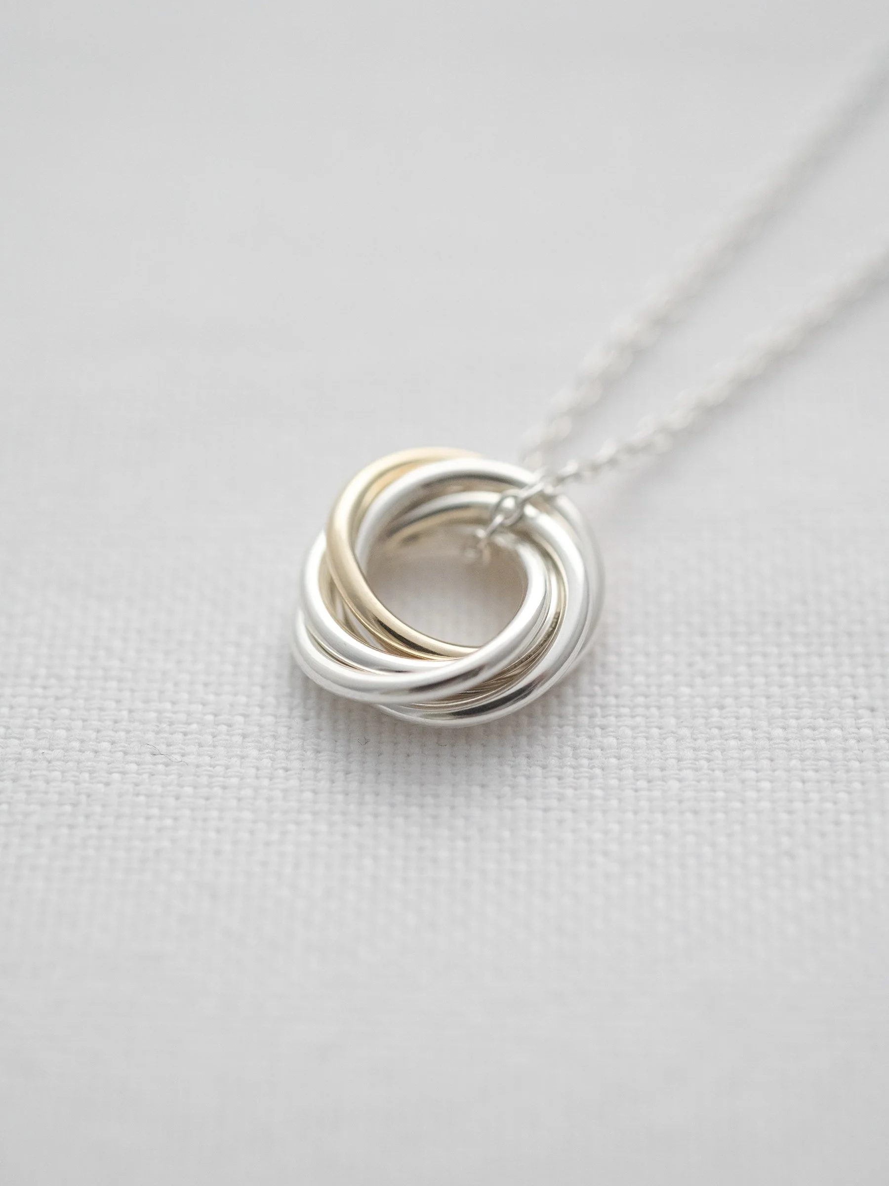 A gold and silver 50th birthday necklace displayed on white material.