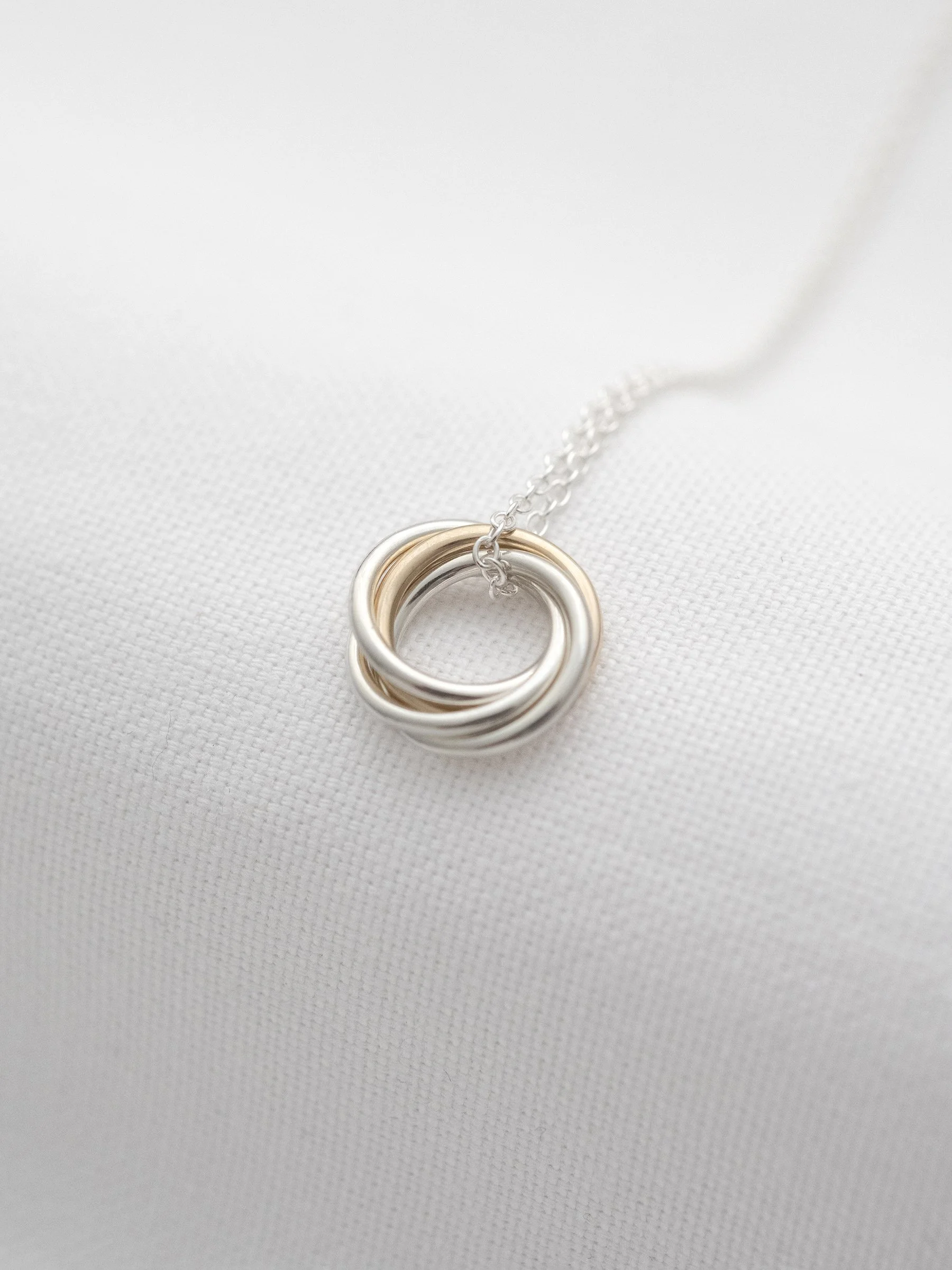 A side view of a gold and silver 40th necklace for a 40th birthday displayed on white material.