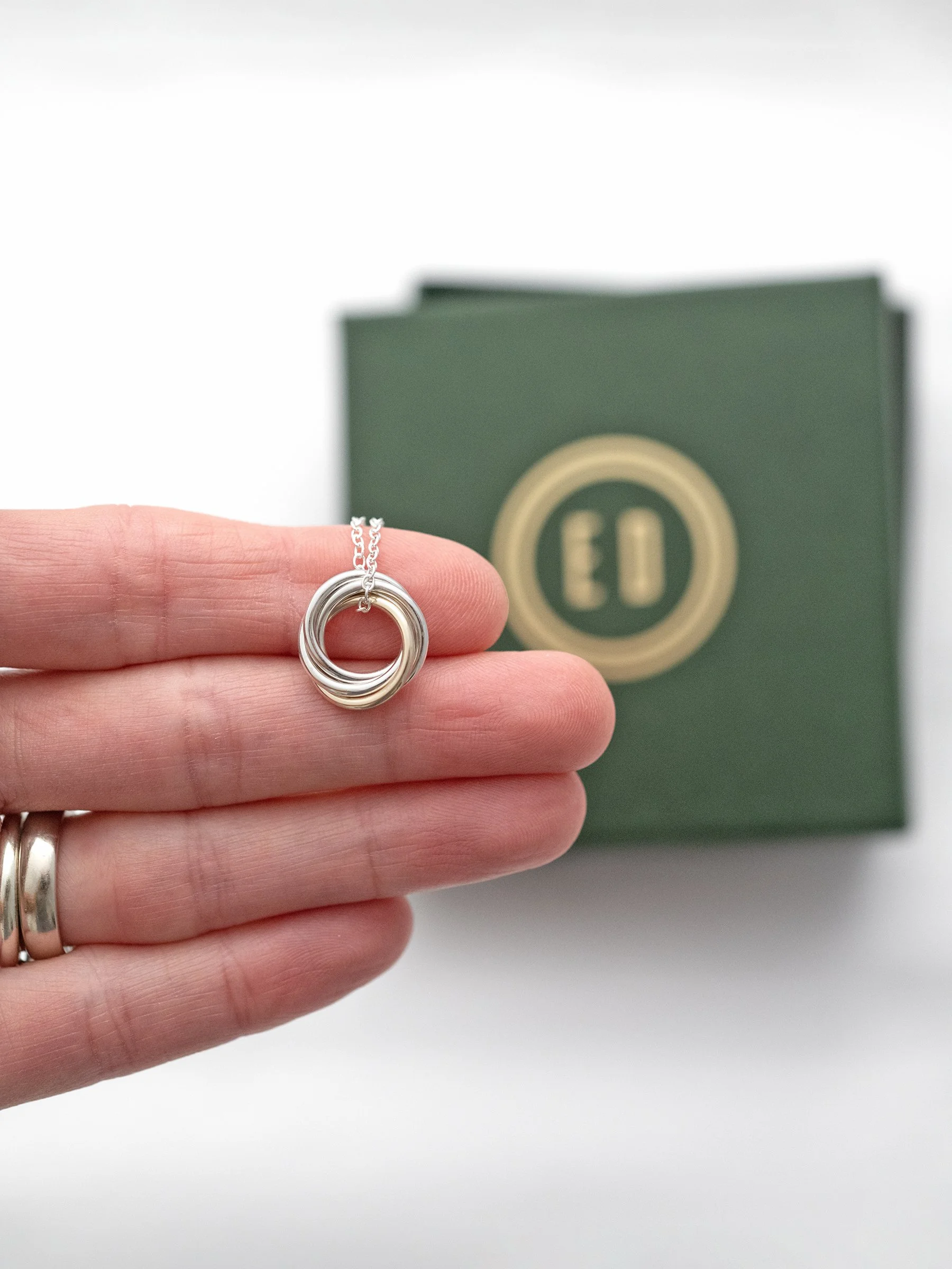 A nine carat gold and silver 40th birthday necklace displayed on a persons hand with the presentation box in the background.