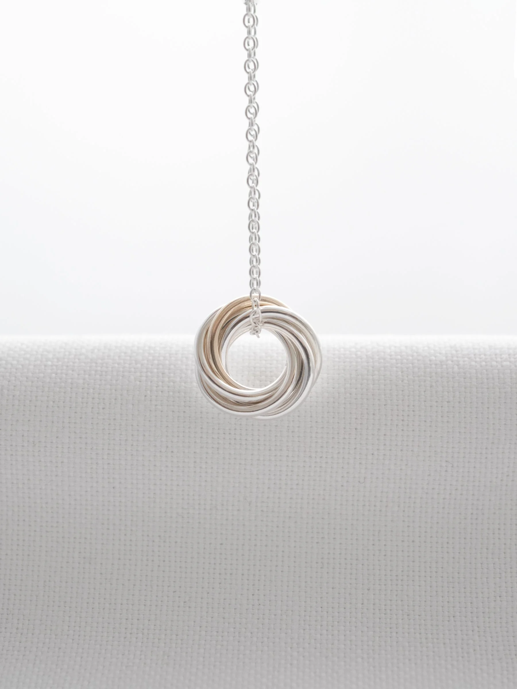 A hallmarked gold and silver 60th necklace hanging over white material.