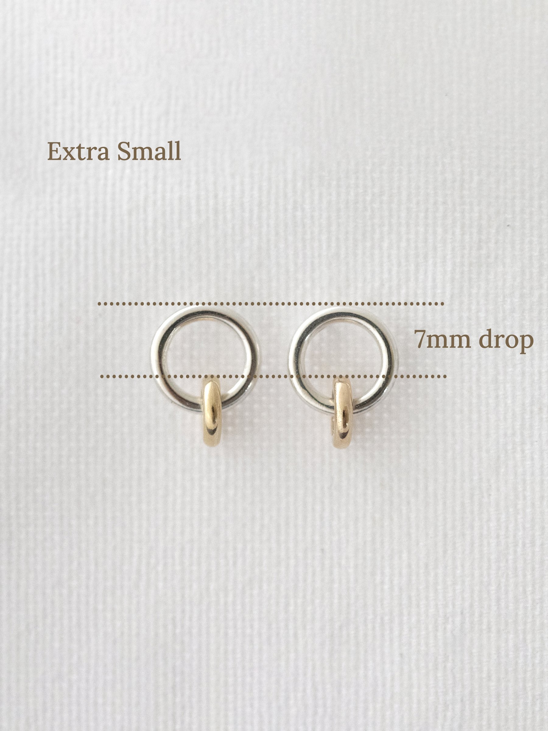 A pair of gold and silver stud earrings with markings showing the size.