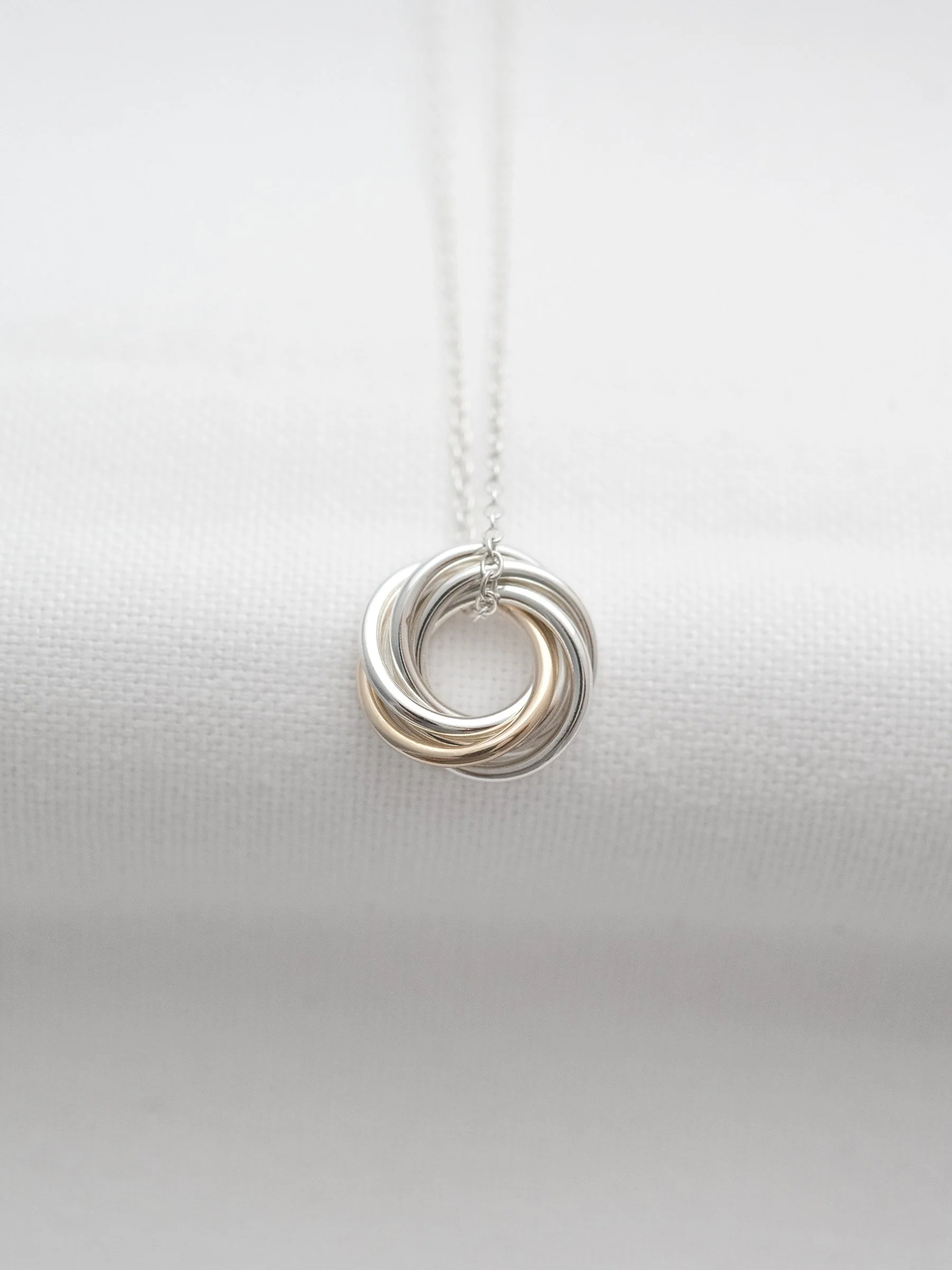 A 60th gold and silver necklace displayed over white material.