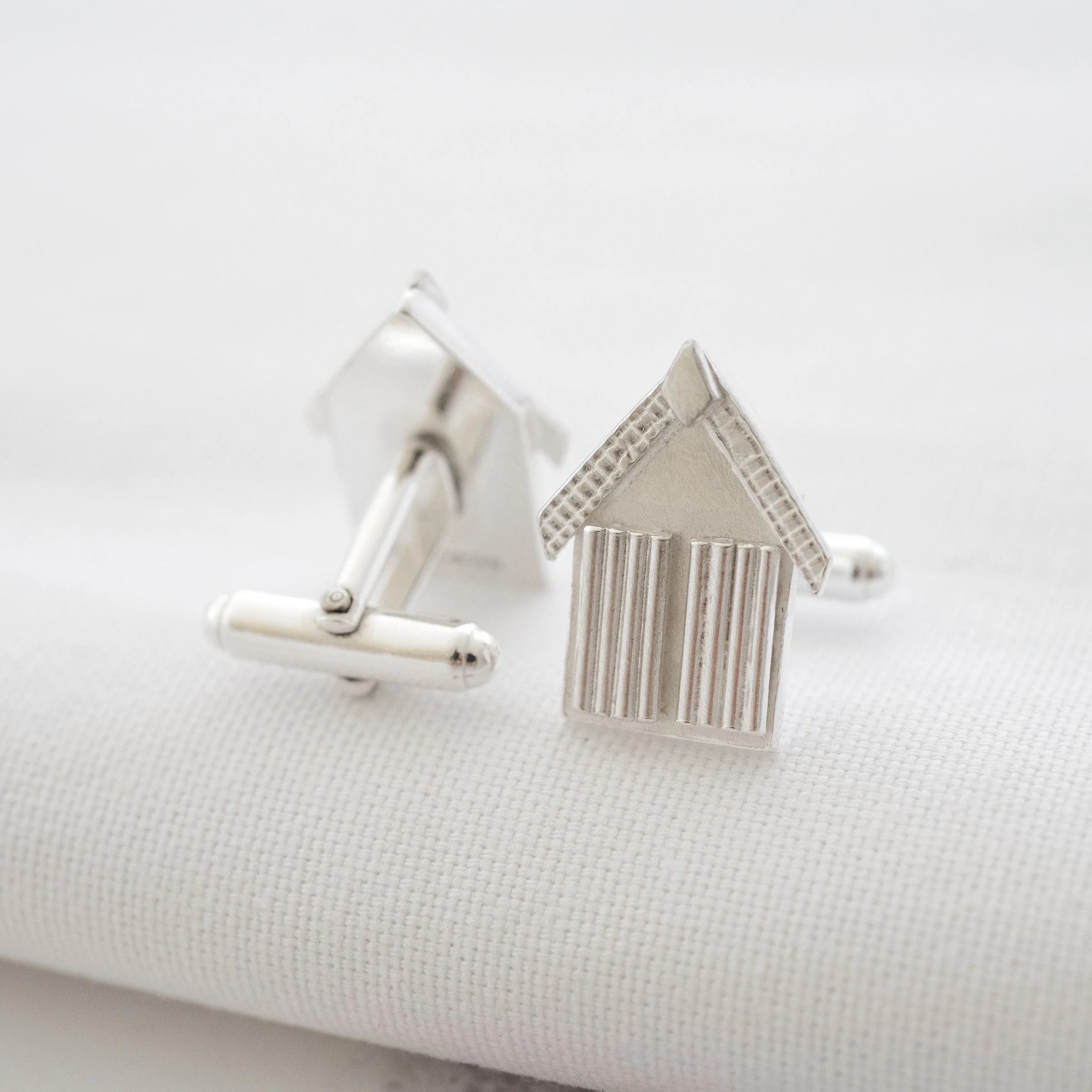 Sterling silver beach hut cufflinks displayed on white material