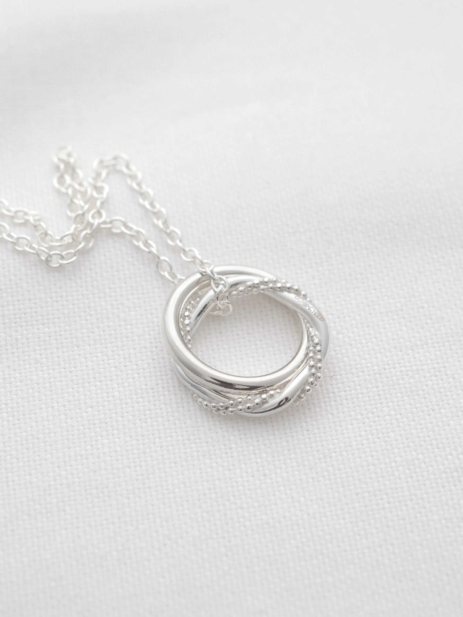 A handmade sterling silver 21st birthday necklace displayed on white material.