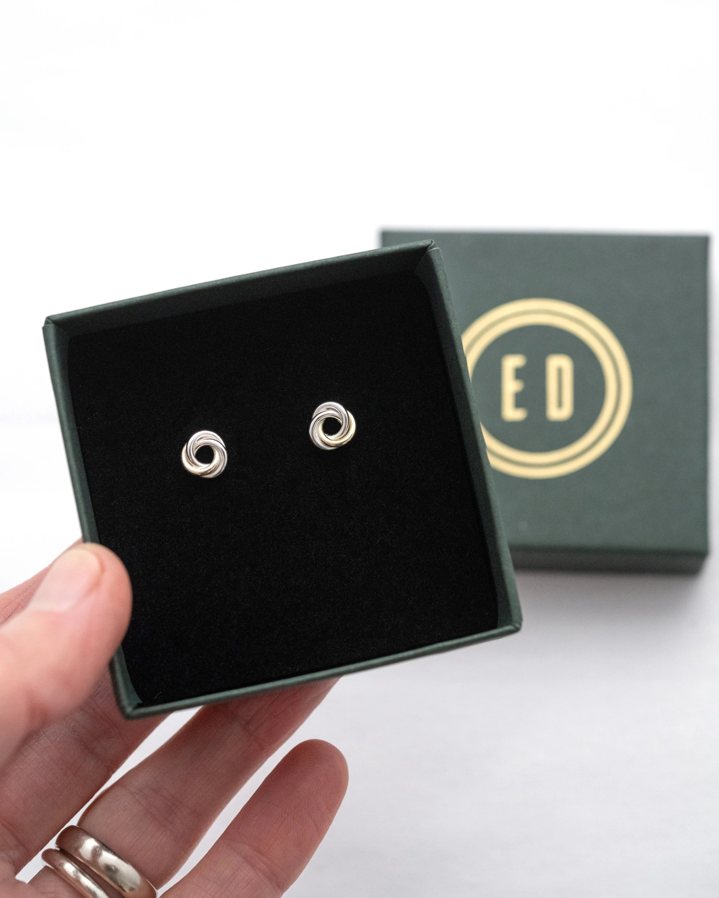 A pair of Elizabeth Designs gold and silver Russian ring stud earrings displayed in the jewellery presentation box.