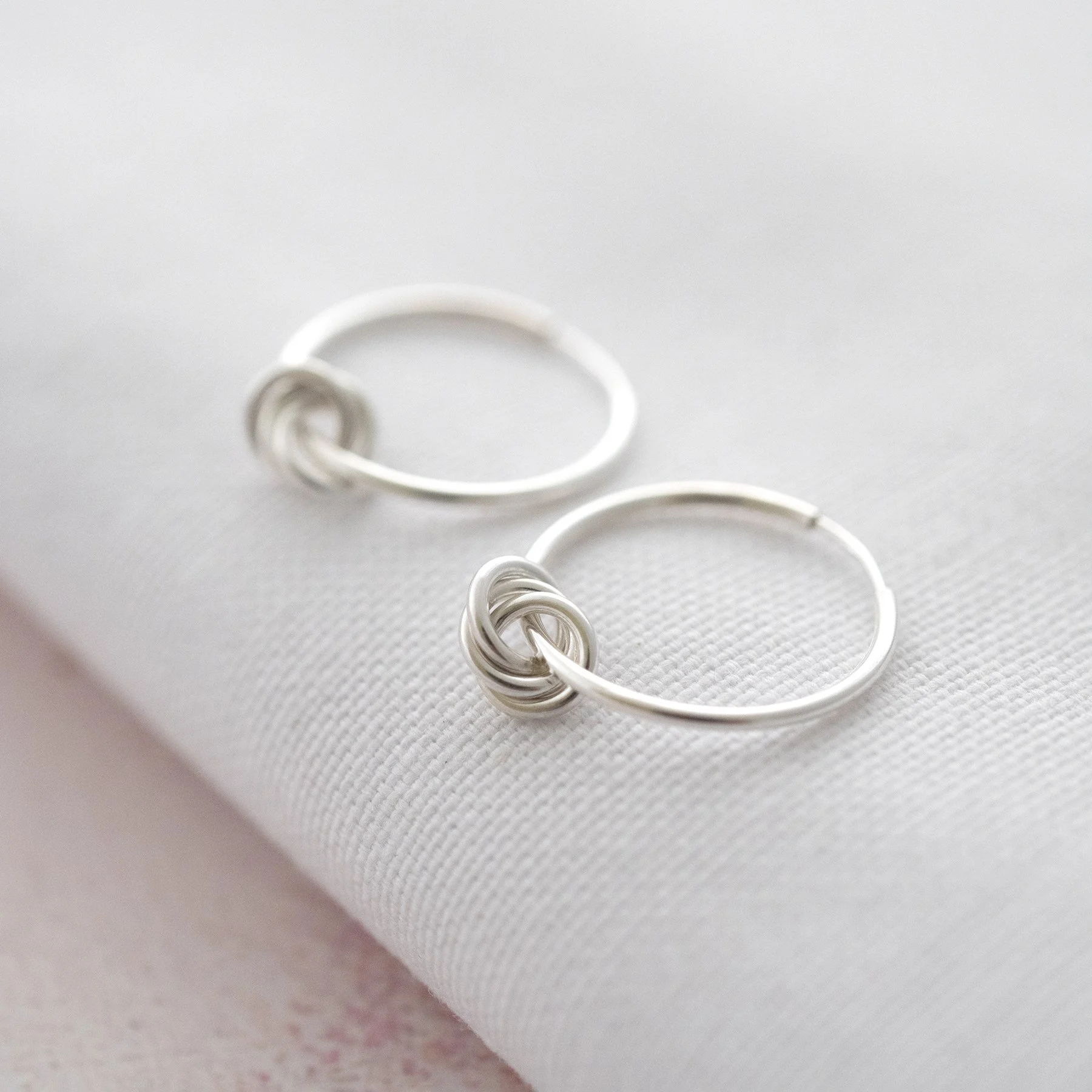 A pair of sterling silver 30th birthday hoop earrings displayed on white material.