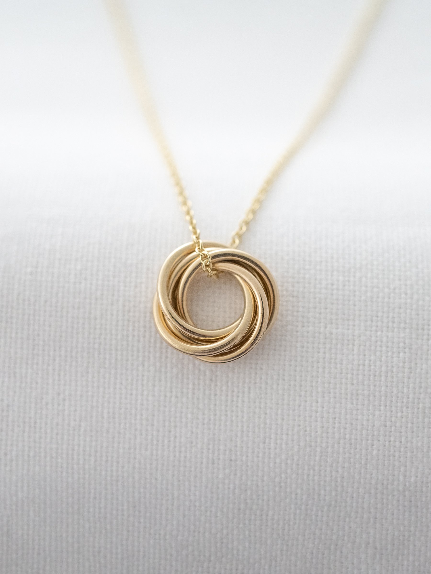 A gold 50th birthday necklace displayed over white material.