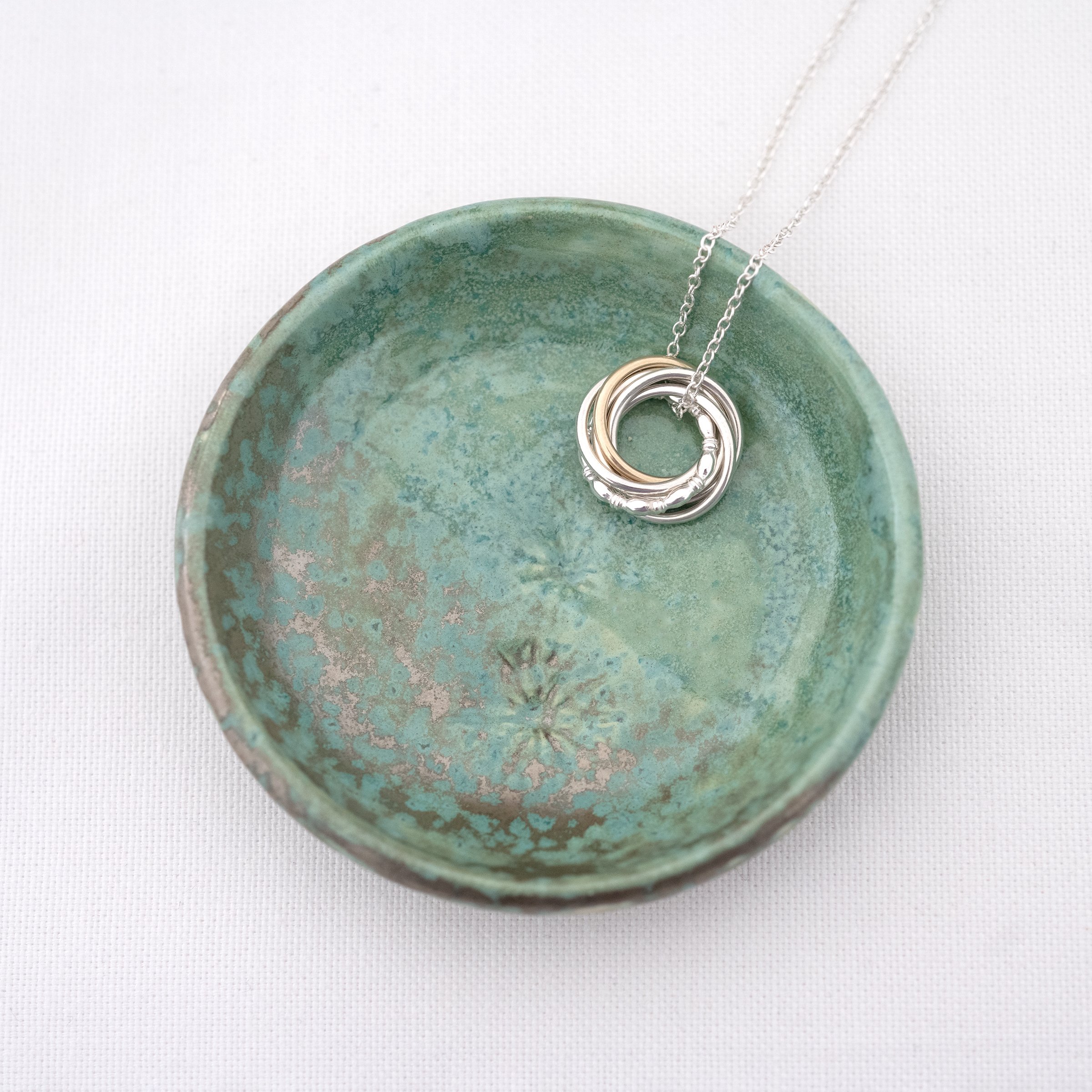 A handmade green jewellery dish displaying a 40th birthday necklace.