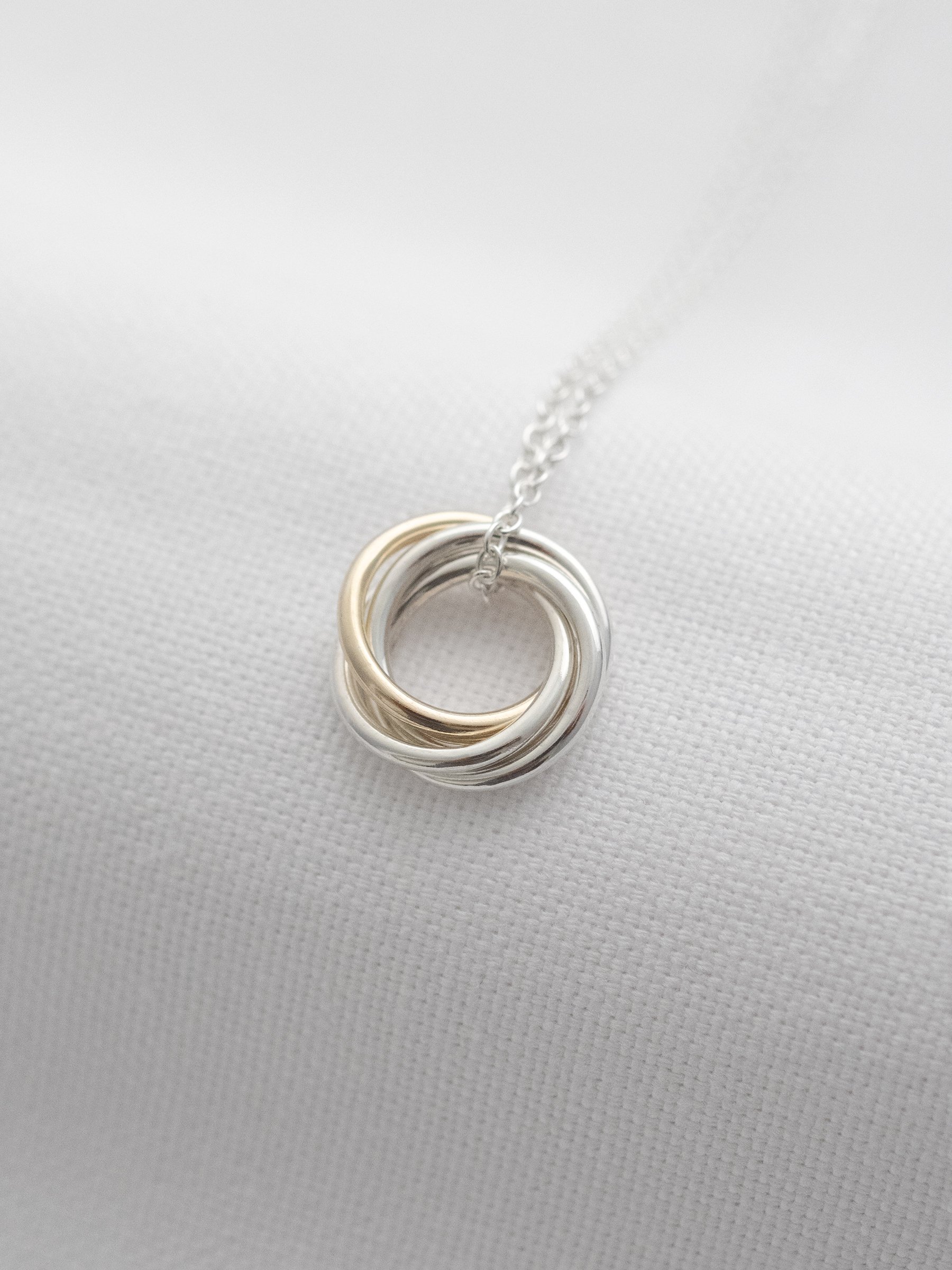 A side view of a gold and silver 40th necklace for a 40th birthday displayed on white material.