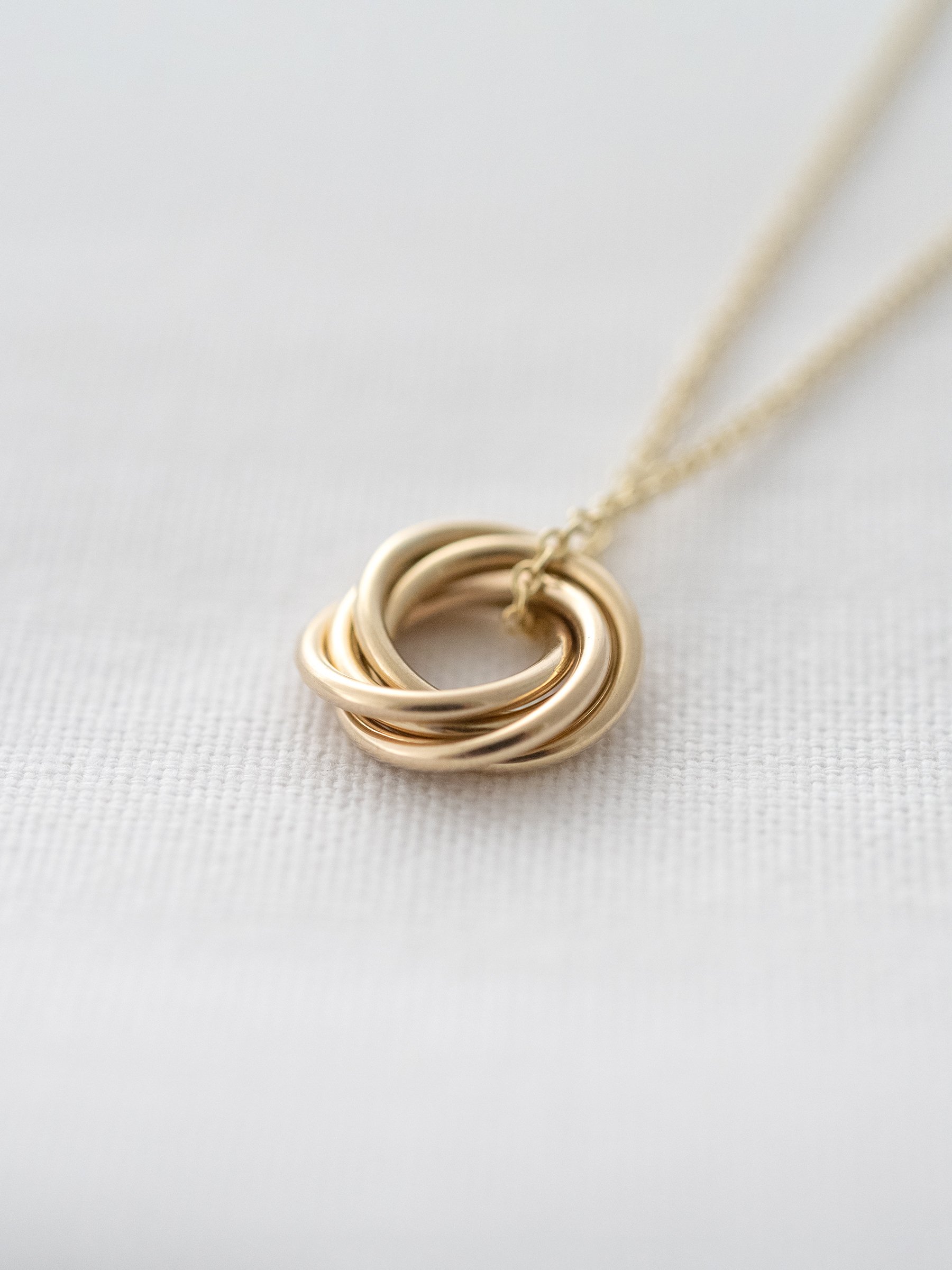 A close up of a 9ct gold 50th necklace displayed on white material.
