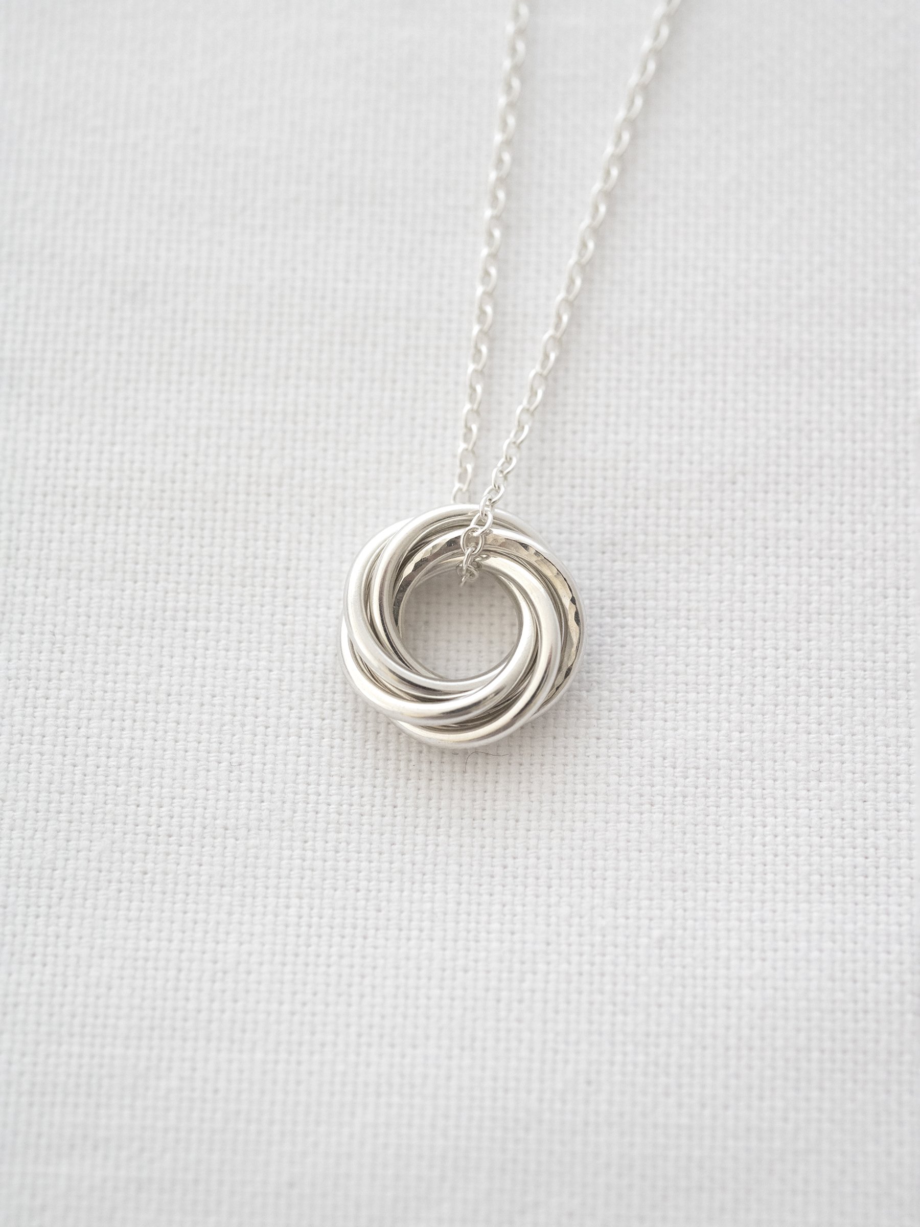 A close up of a sterling silver 60th birthday necklace displayed on white material.
