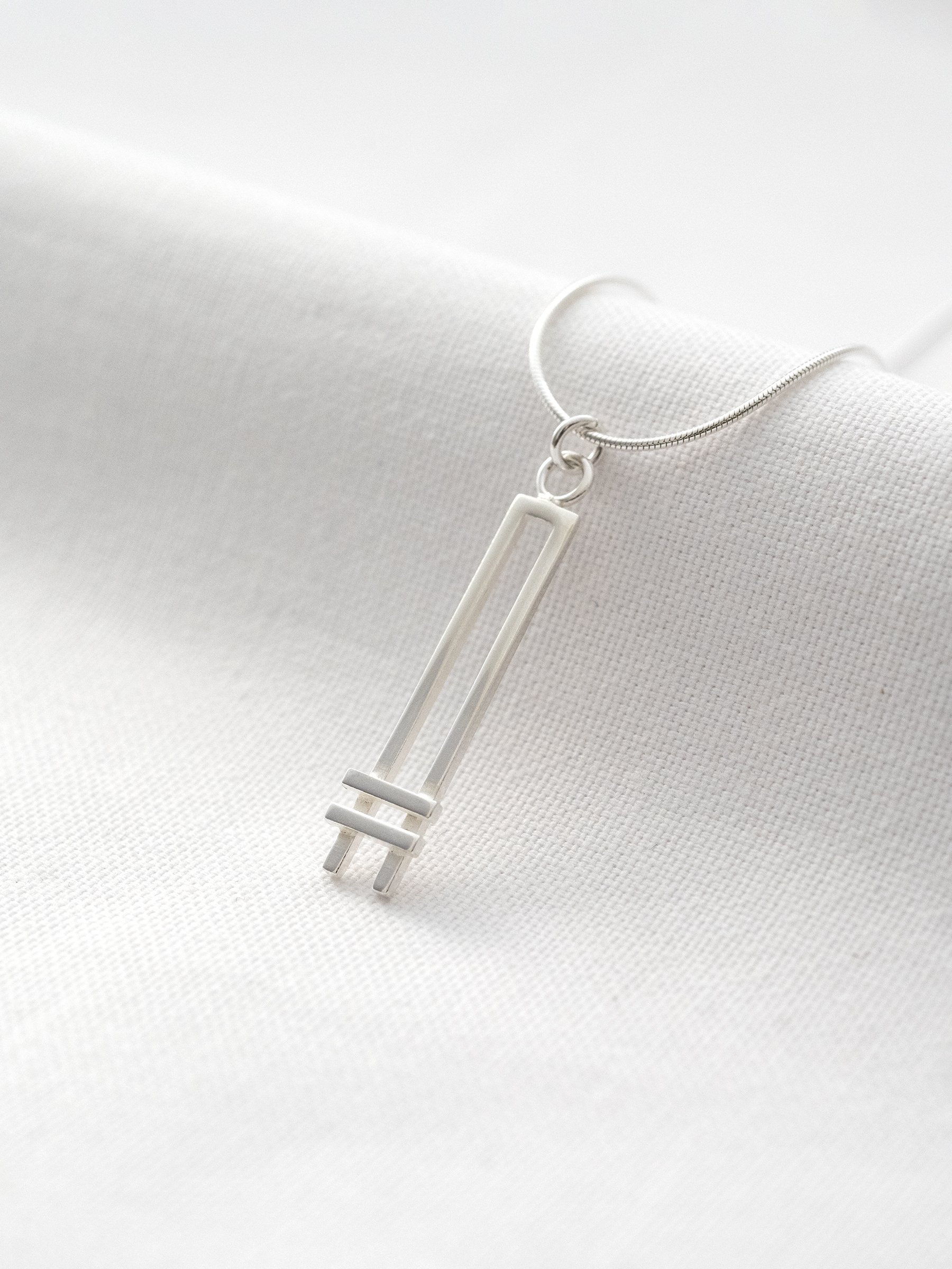 A sterling silver Art Deco style necklace displayed against white material.