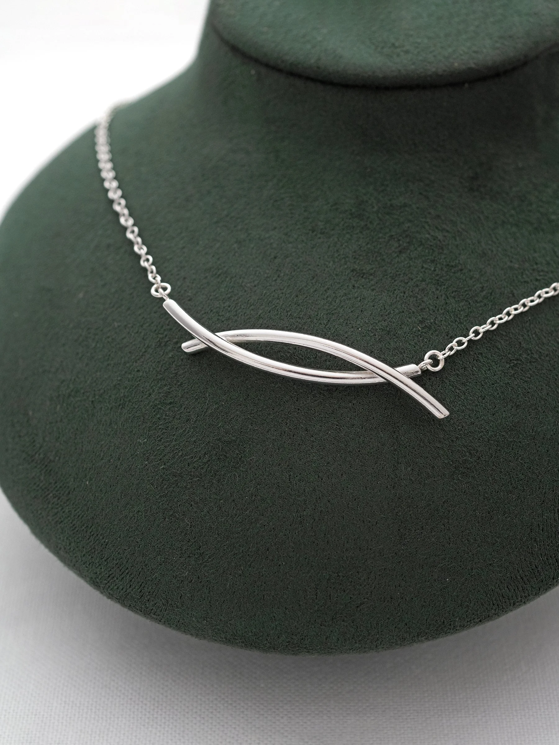 A silver entwined twist necklace displayed on a green background.