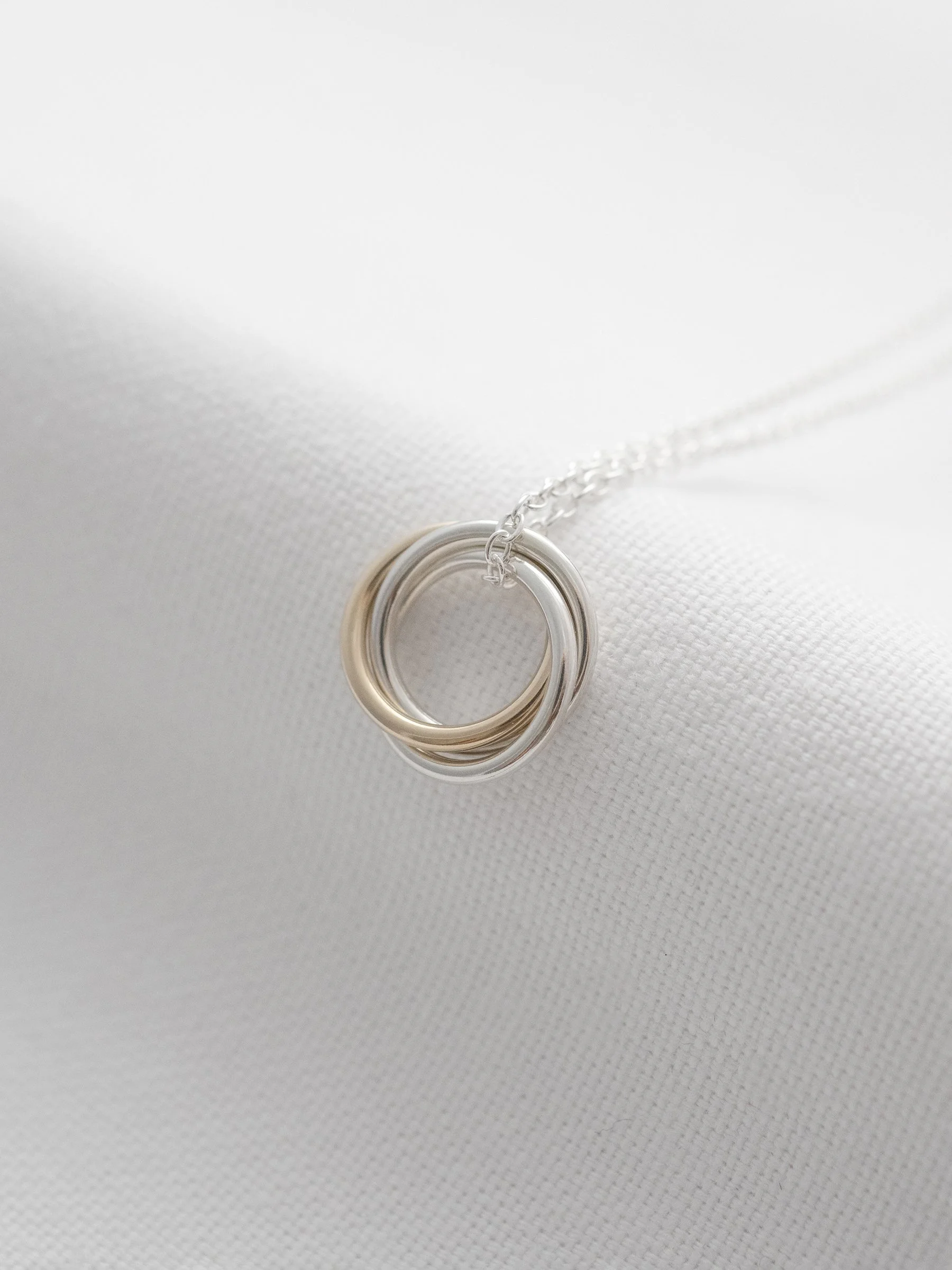 A side view of a hallmarked gold and silver 30th necklace displayed on white material.