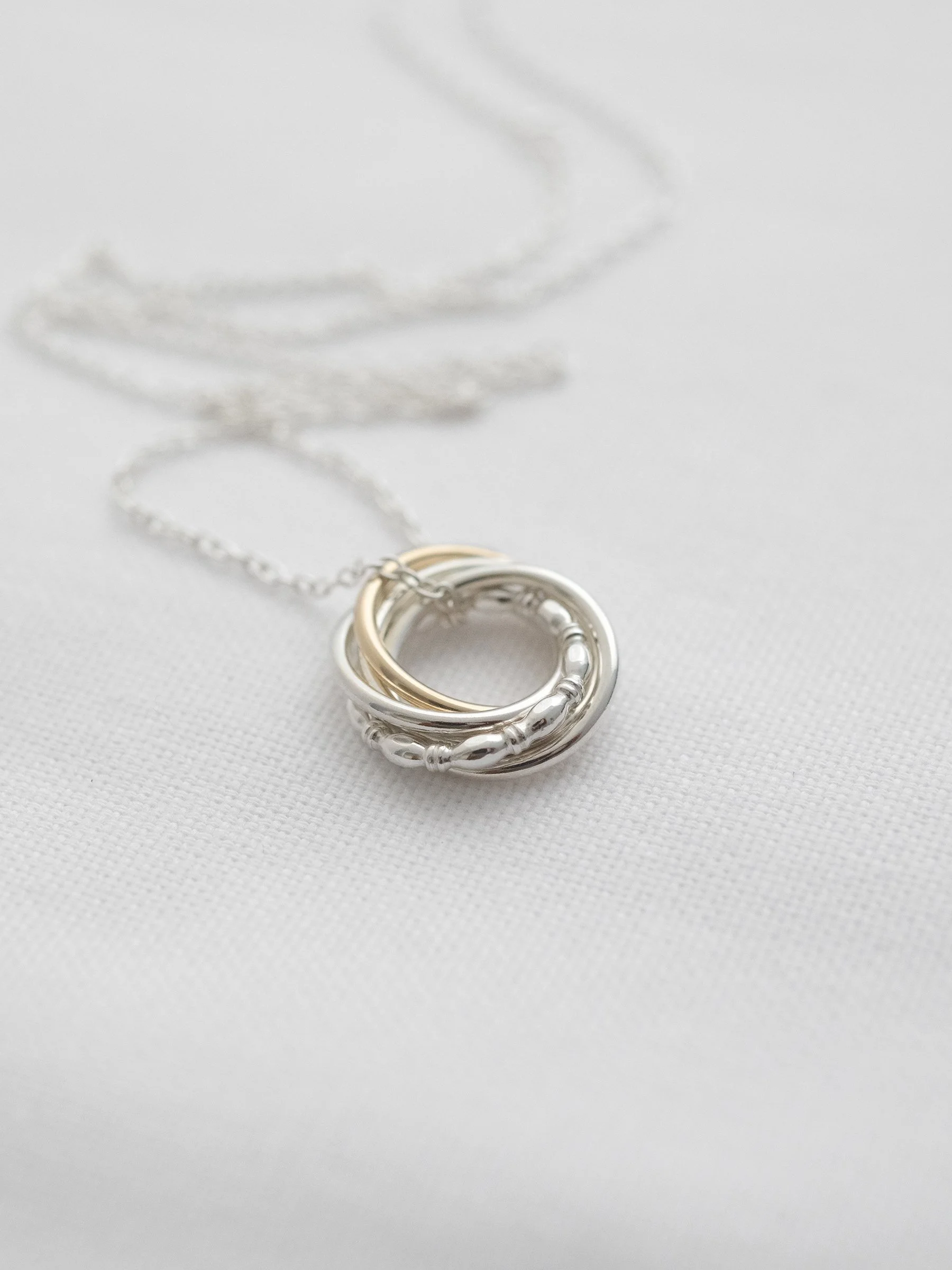 A close up of a 50th gold and silver birthday necklace on white material.