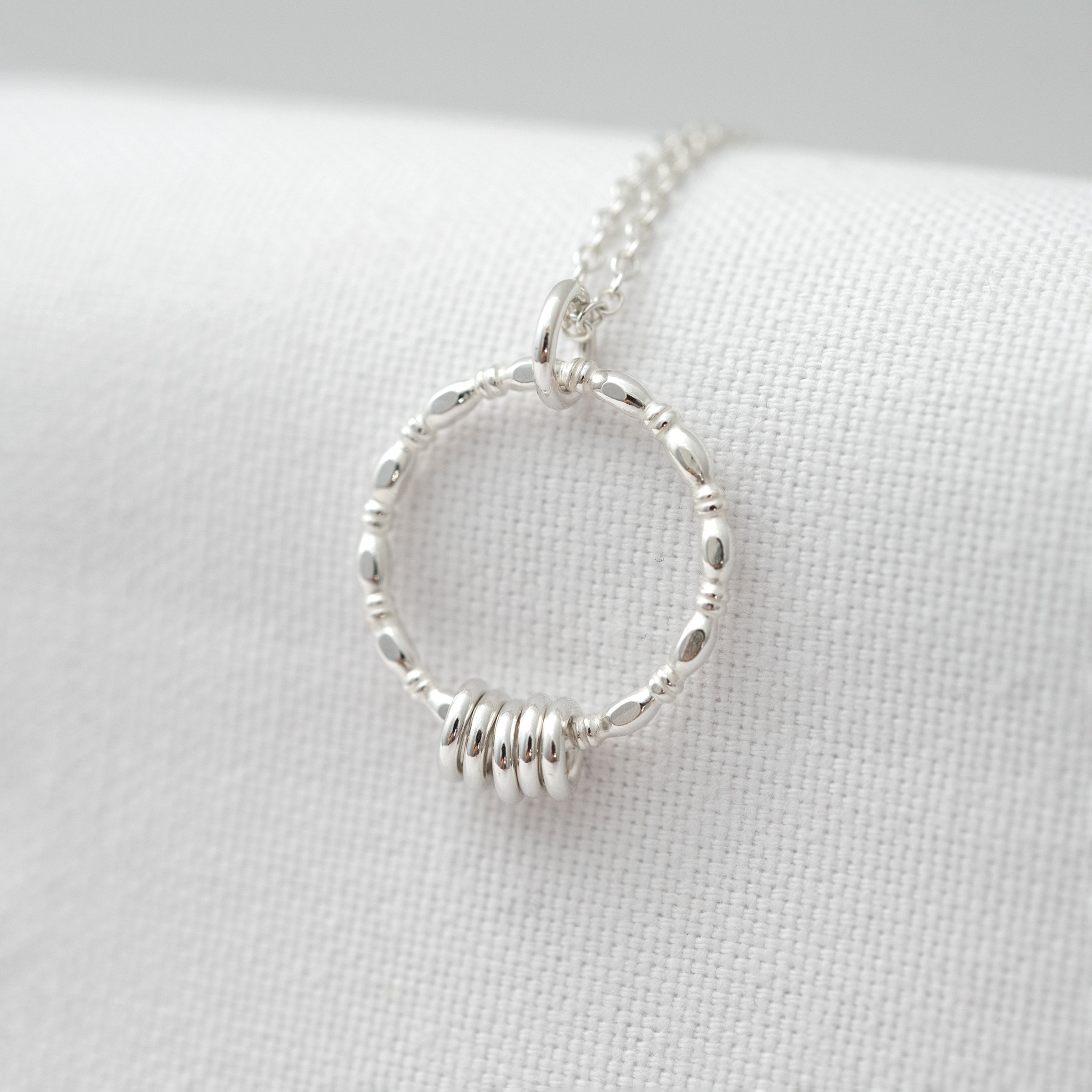 A sterling silver 50th birthday necklace displayed over white material.