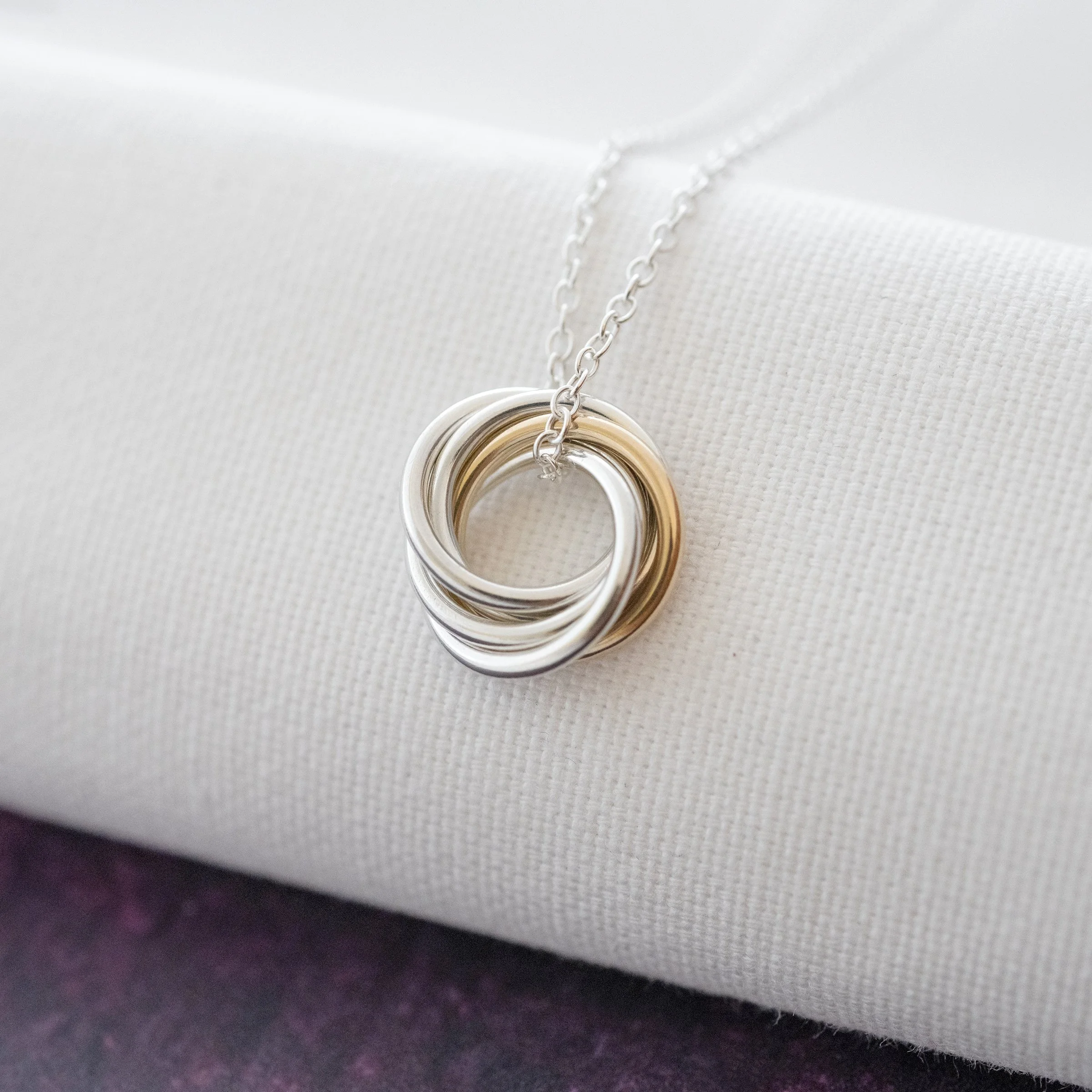 A gold and silver 50th Birthday necklace displayed over white material.