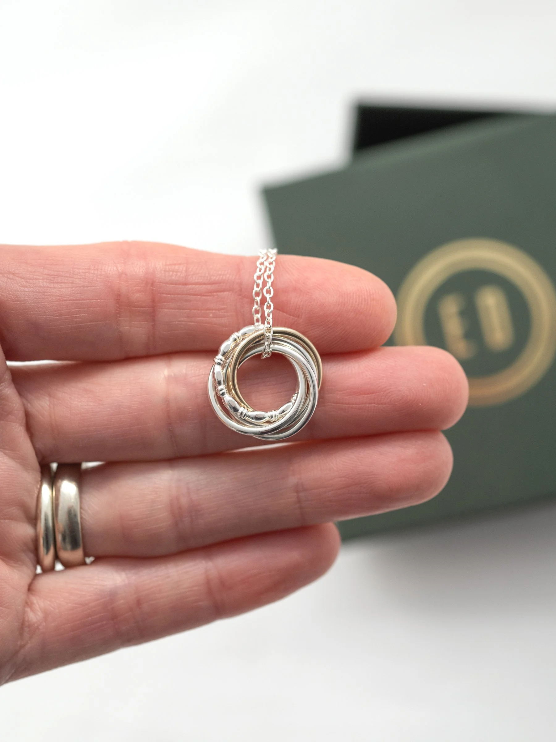 A person displaying a 50th birthday necklace in their hand with a jewellery presentation box in the background.