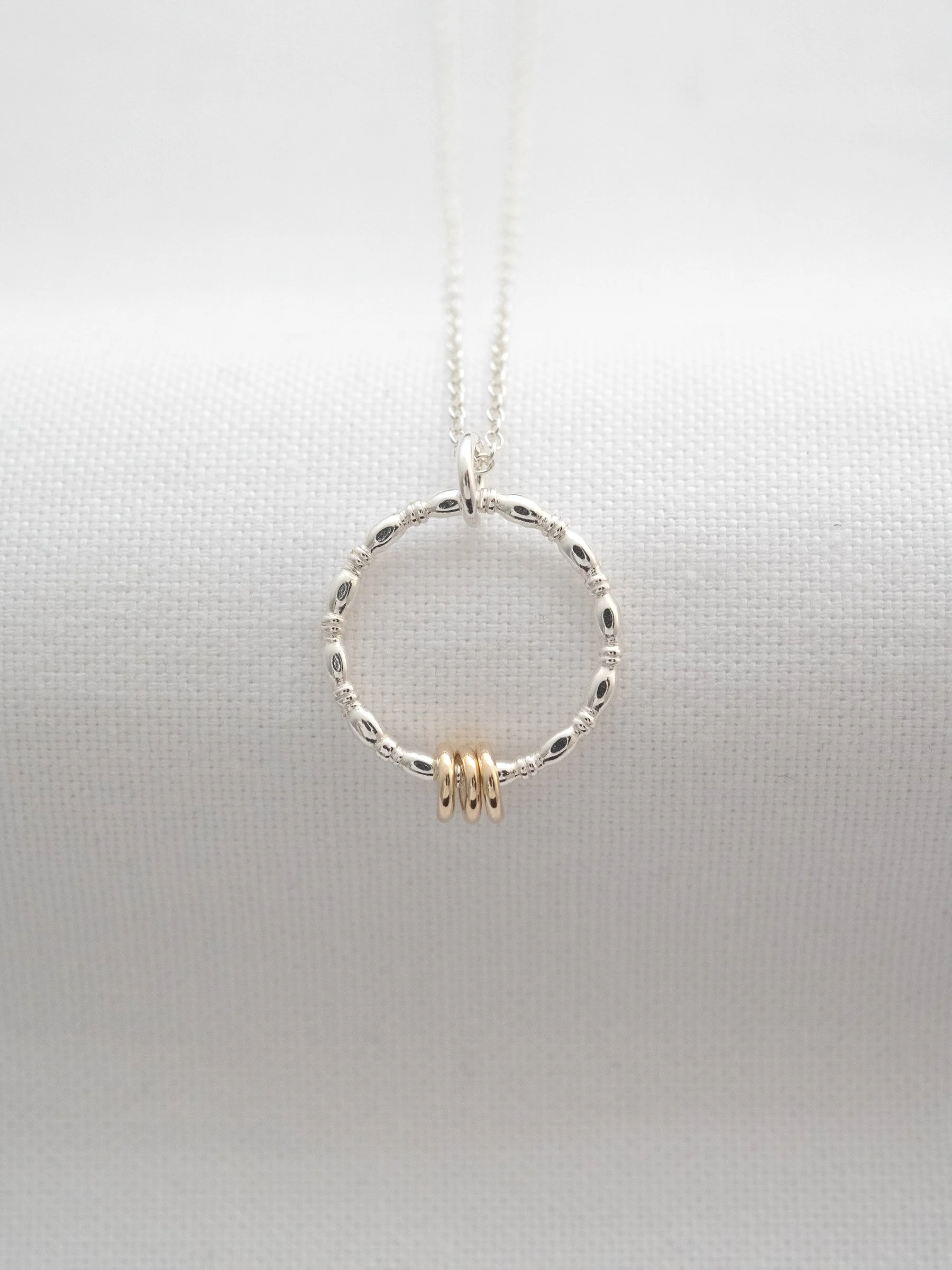 A unique 30th gold and silver birthday necklace displayed on white material.