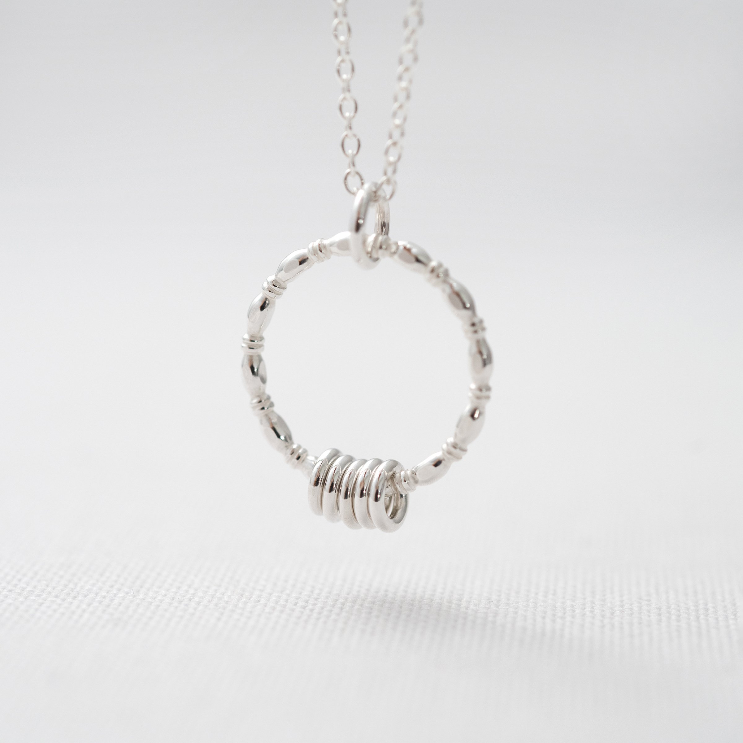A sterling silver 50th birthday necklace hanging over white material.