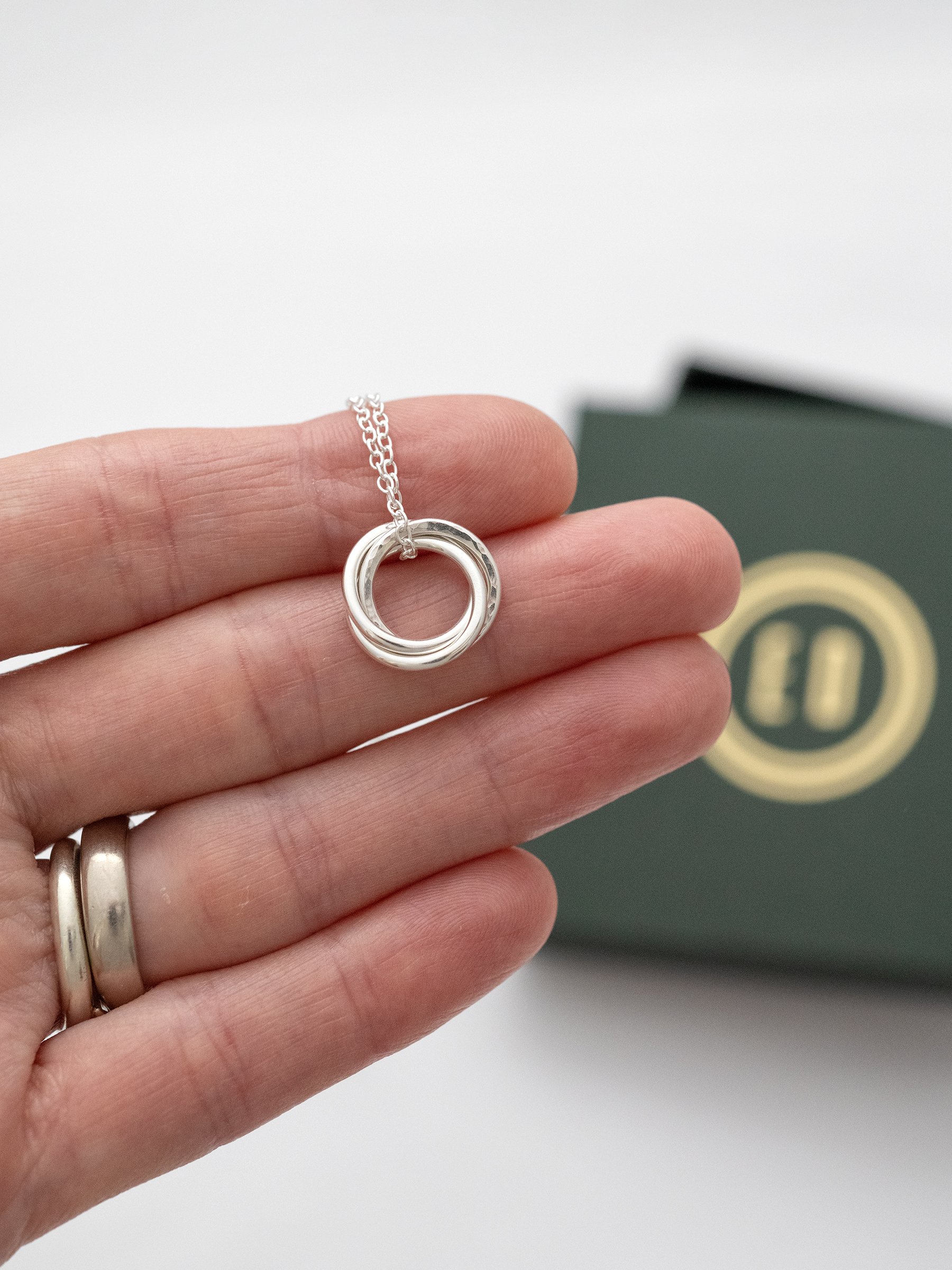 A sterling silver 30th necklace displayed over a persons hand with the jewellery presentation box in the background.