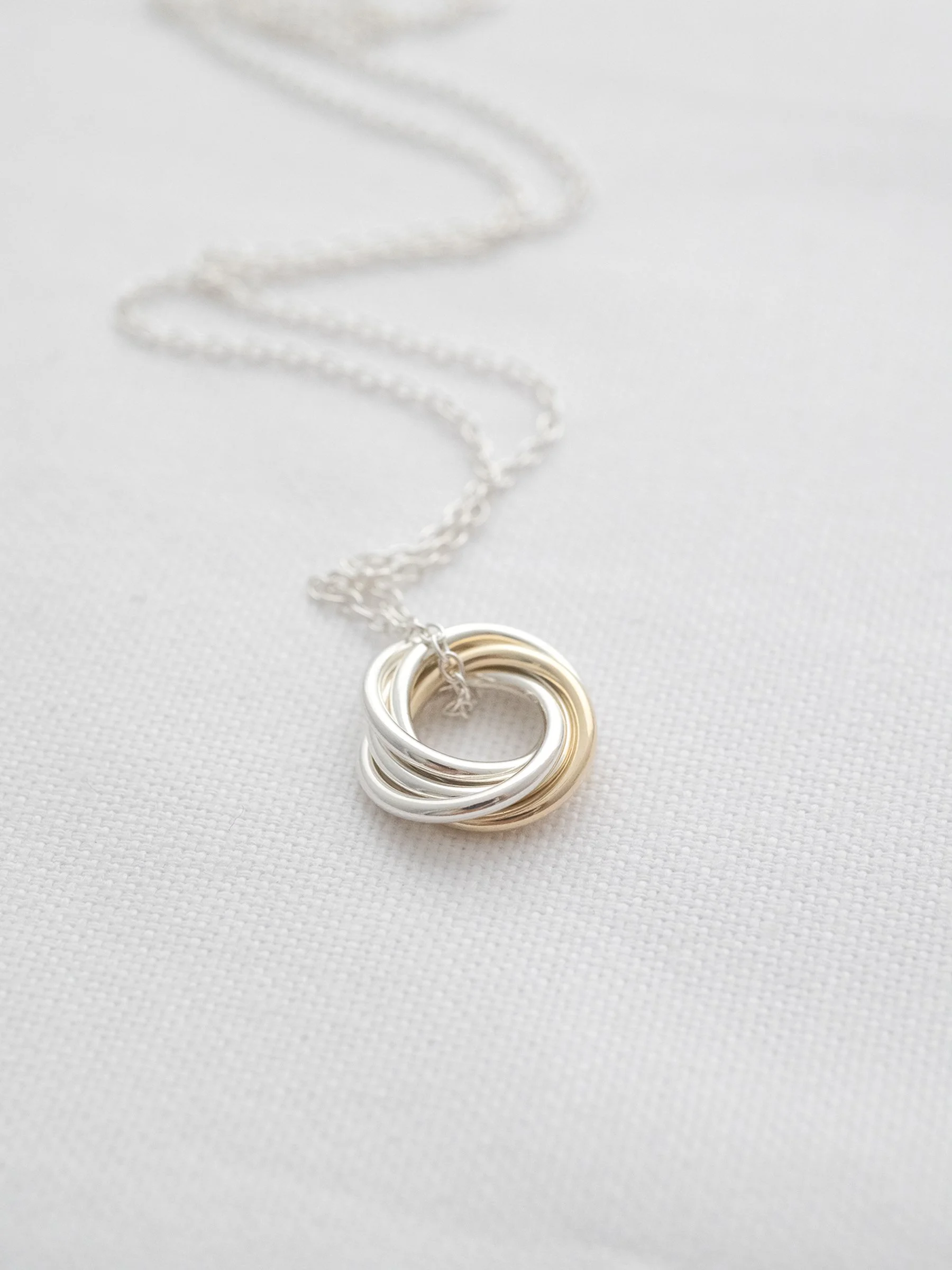 A 50th gold and silver birthday necklace displayed with the silver chain against white material.