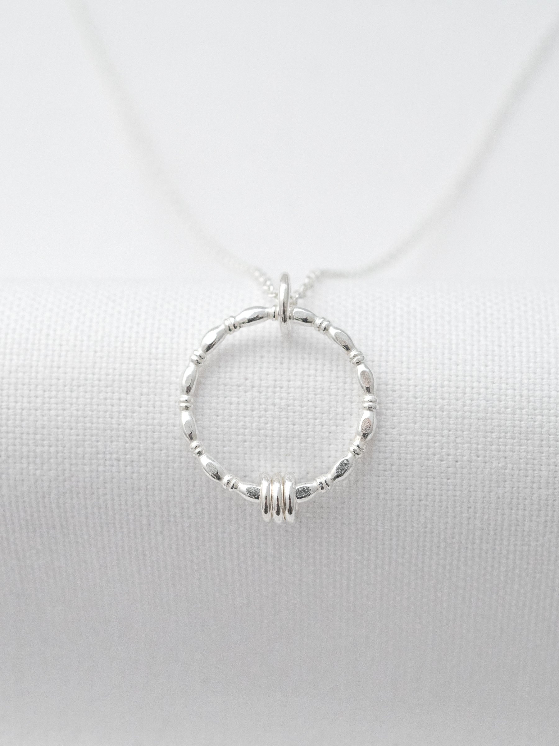 A sterling silver 30th birthday necklace displayed over white material.